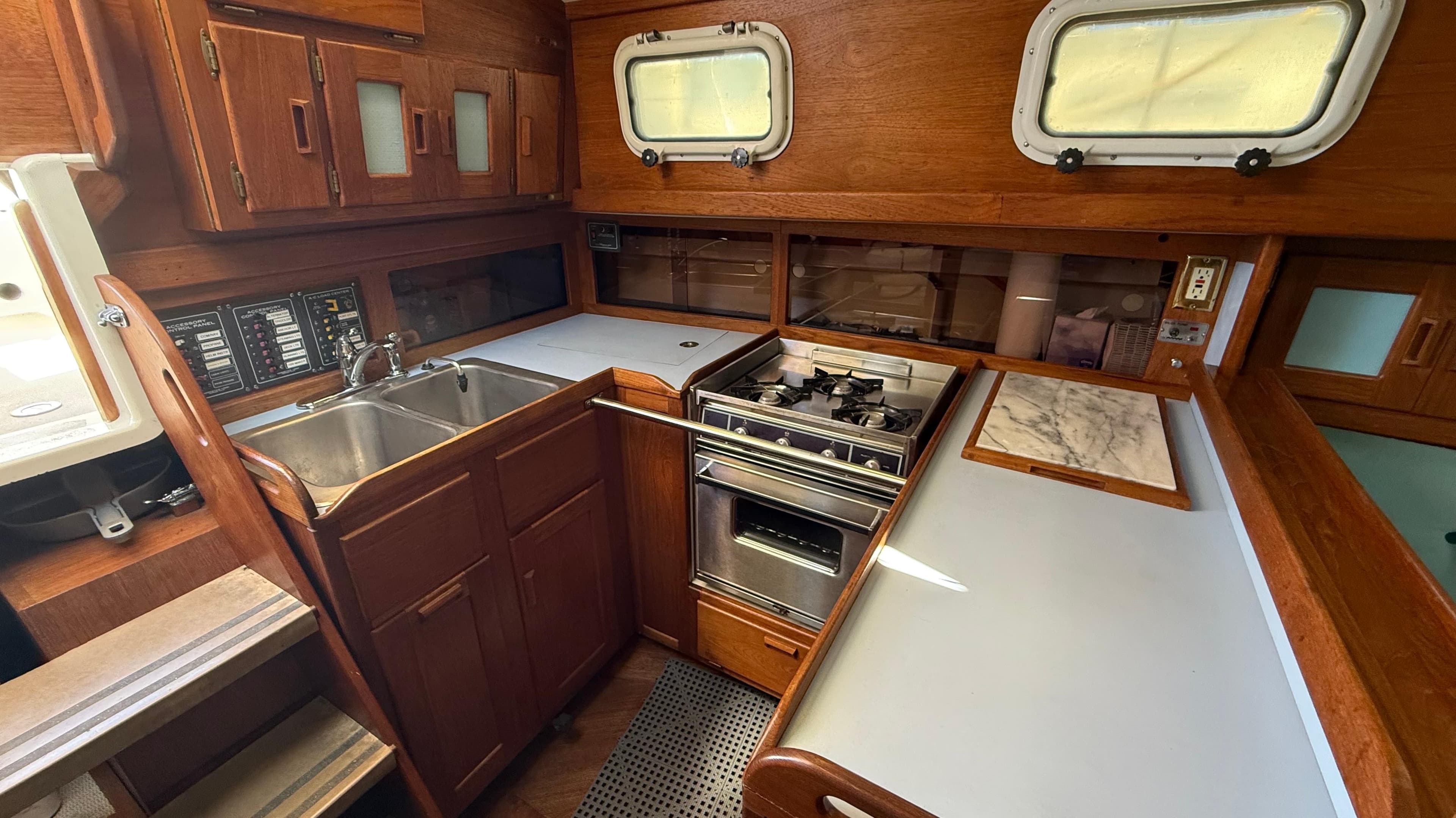 1984 Cascade 36 yacht kitchen with wood cabinetry, dual sink, stove, and countertop.