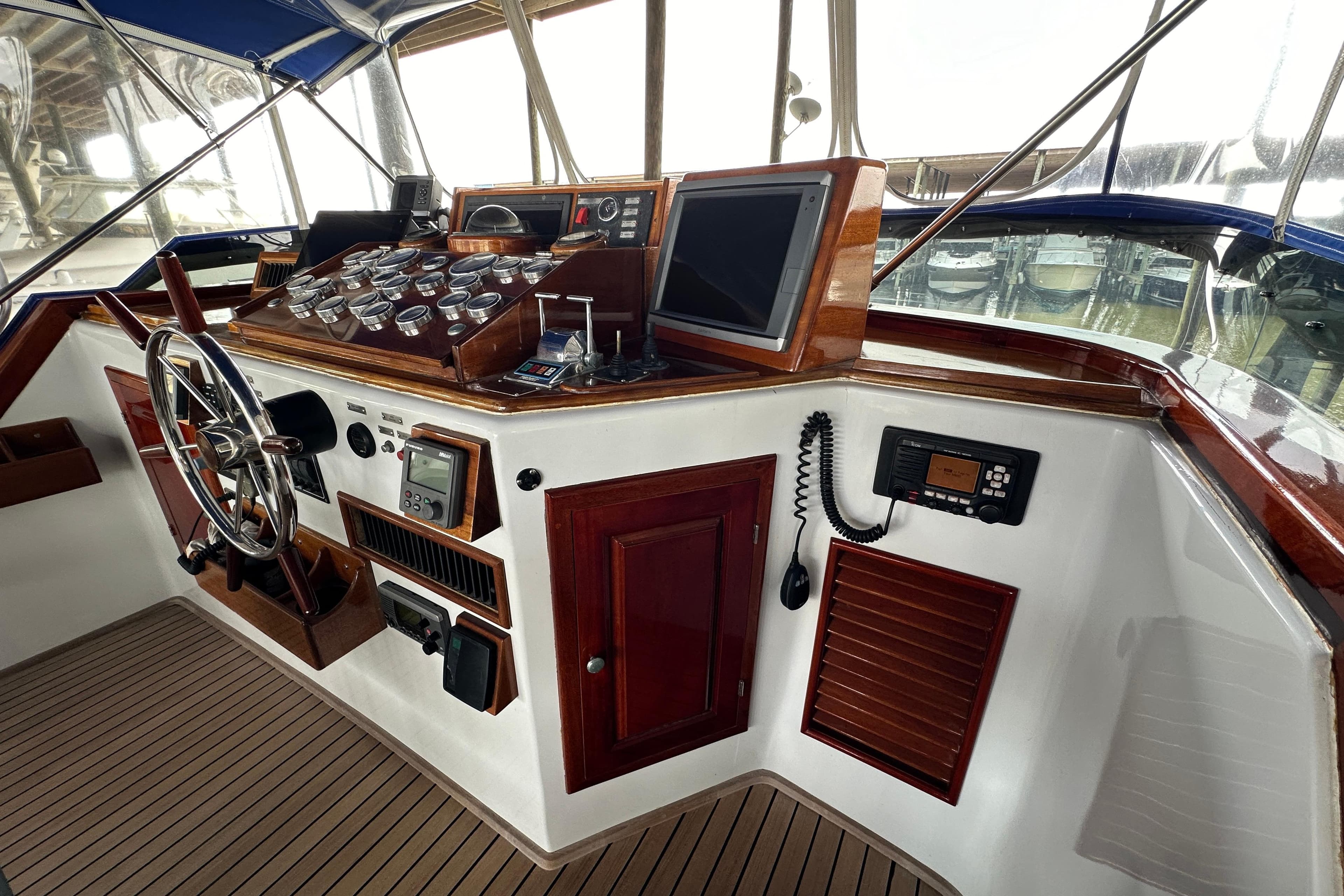 Cockpit of a 1980 Bertram 58 Convertible yacht with classic wooden dashboard and steering wheel.