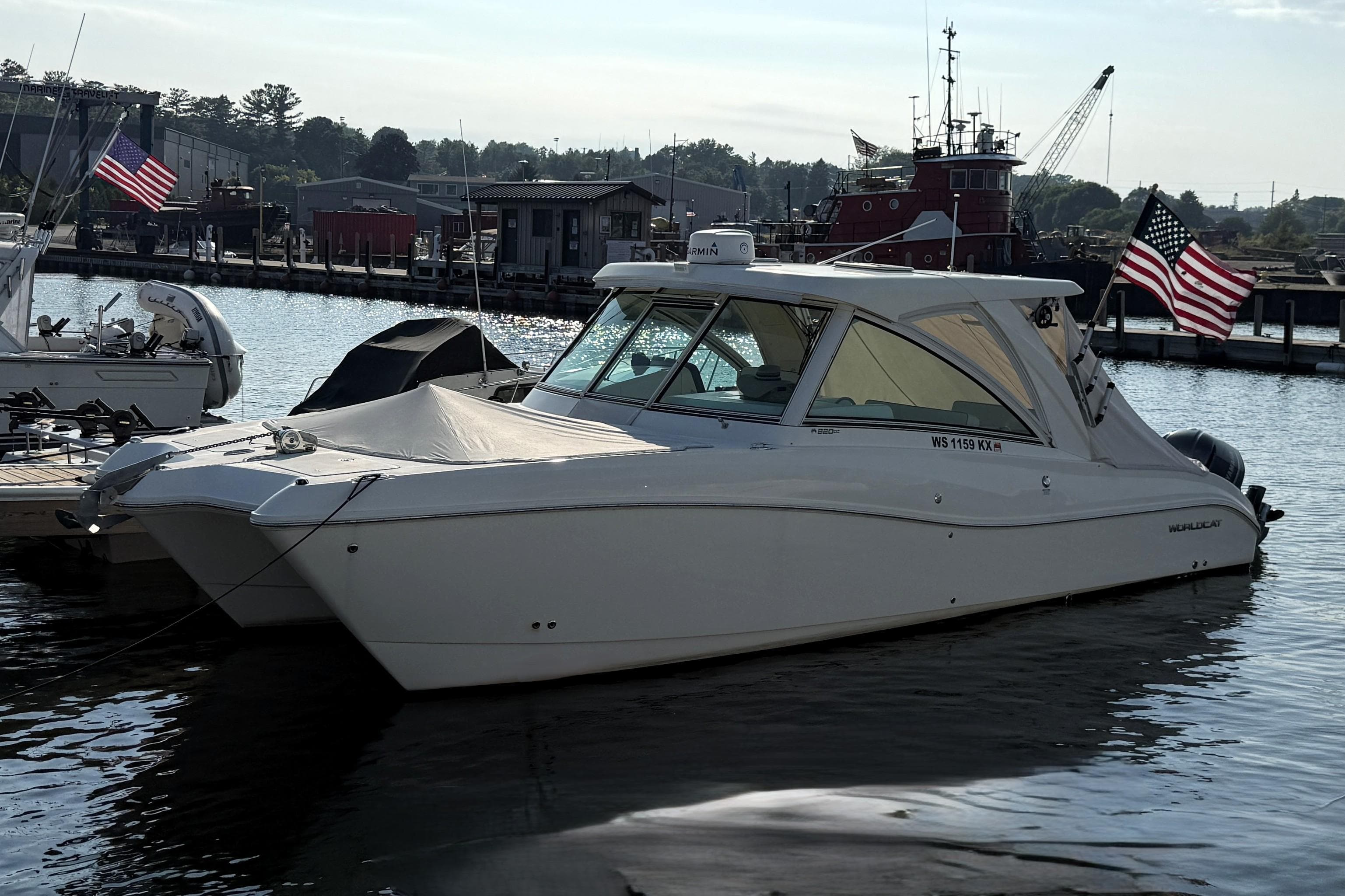 2016 World Cat 320 DC boat docked in a marina with American flags.