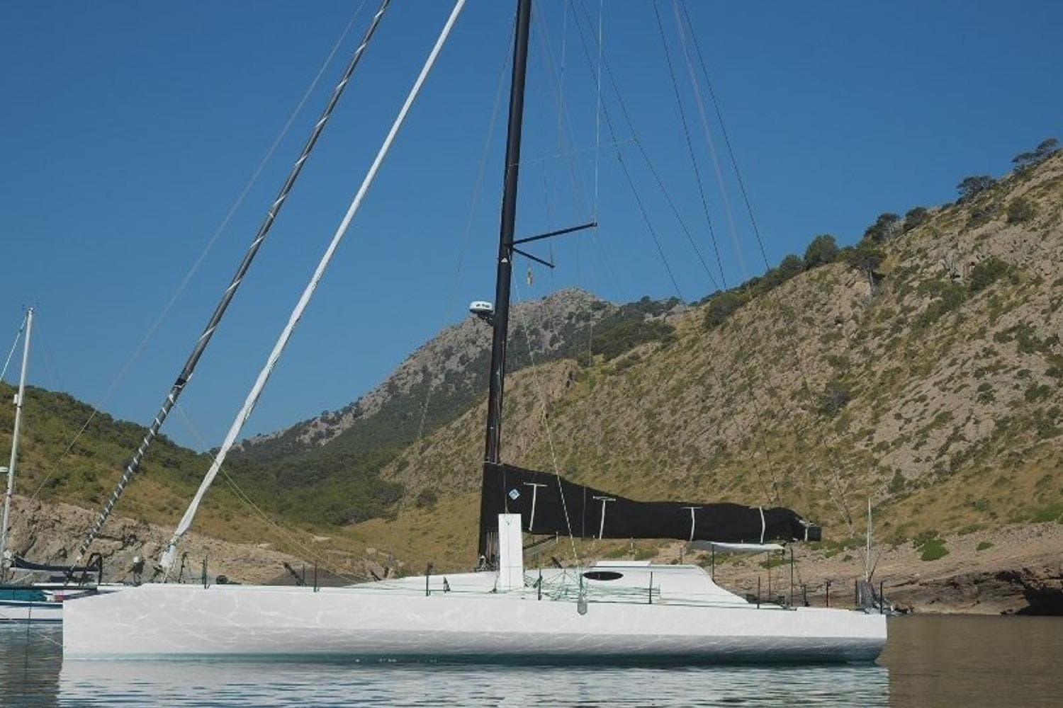 2023 JMV Open 53 sailboat anchored in a scenic mountainous bay.