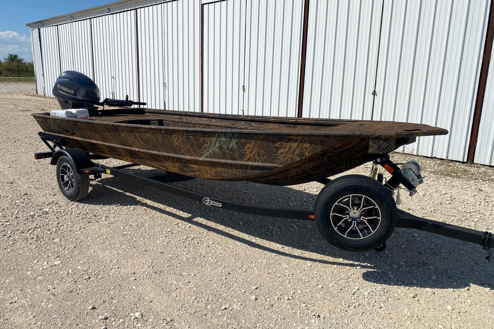 2026 G3 16DK boat on trailer with Yamaha motor, parked on gravel near metal building.