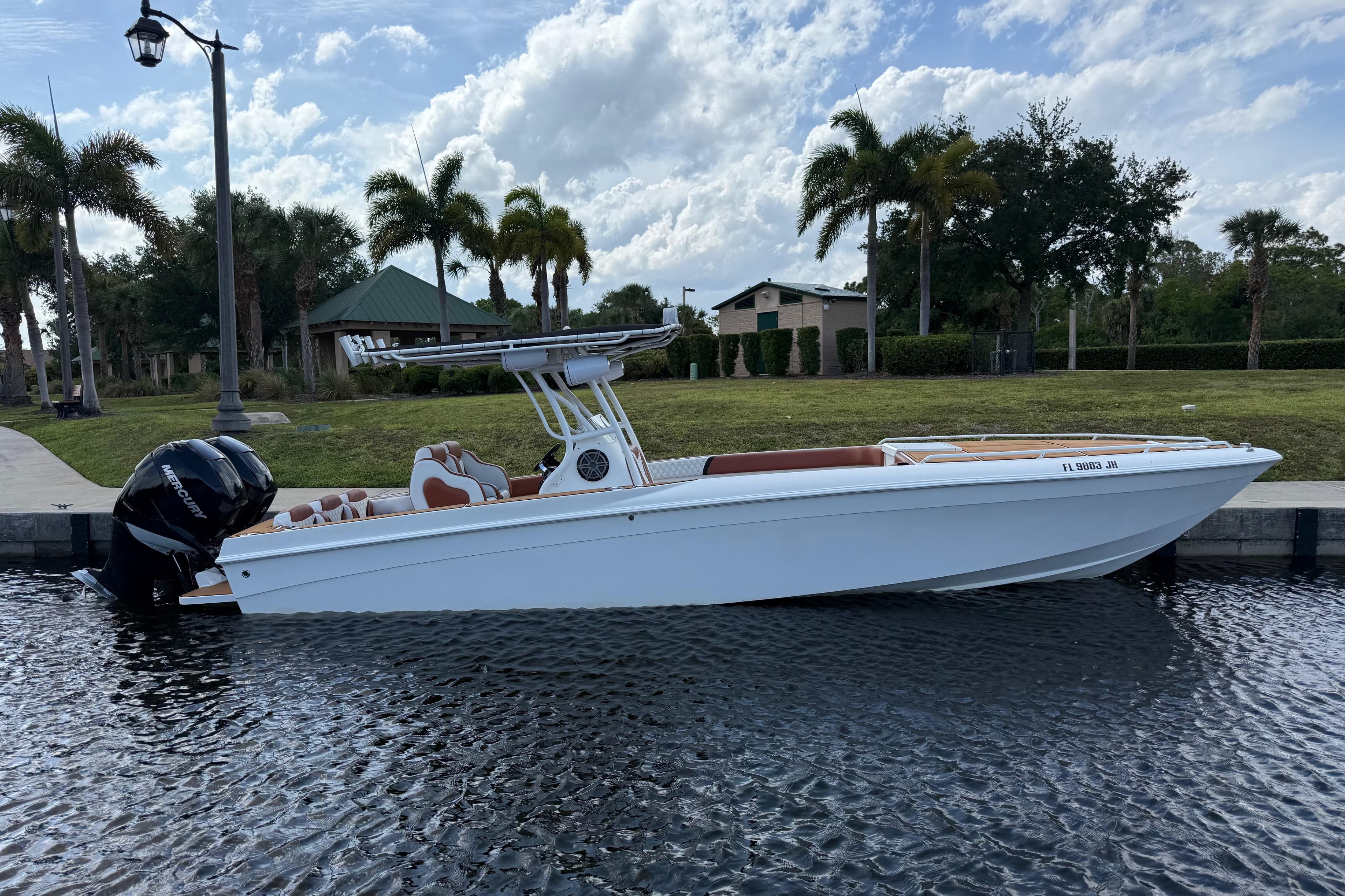 2005 Renegade 29CC boat docked by a scenic waterfront with palm trees.