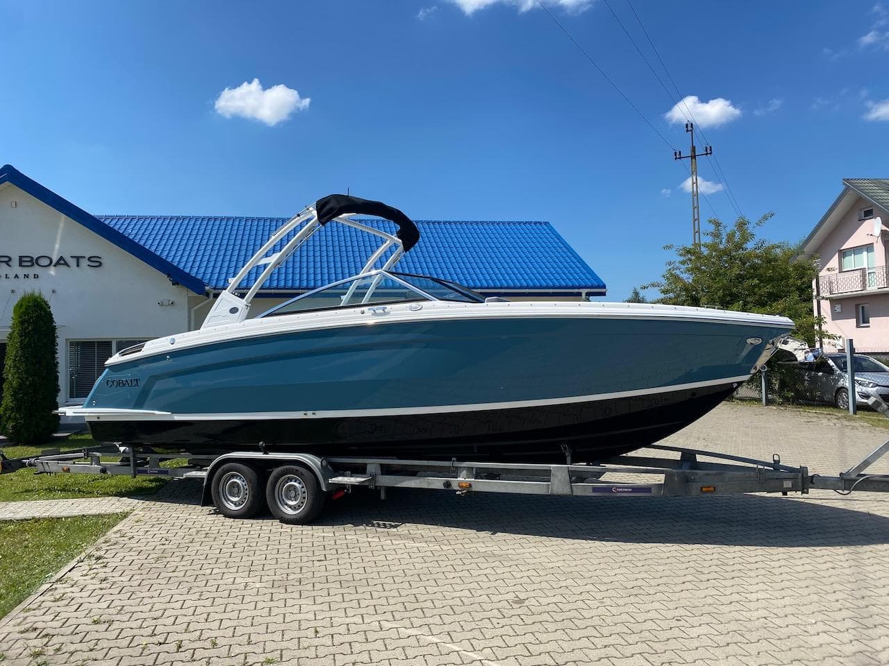 2022 Cobalt R8 boat on a trailer in front of a building with a blue roof.