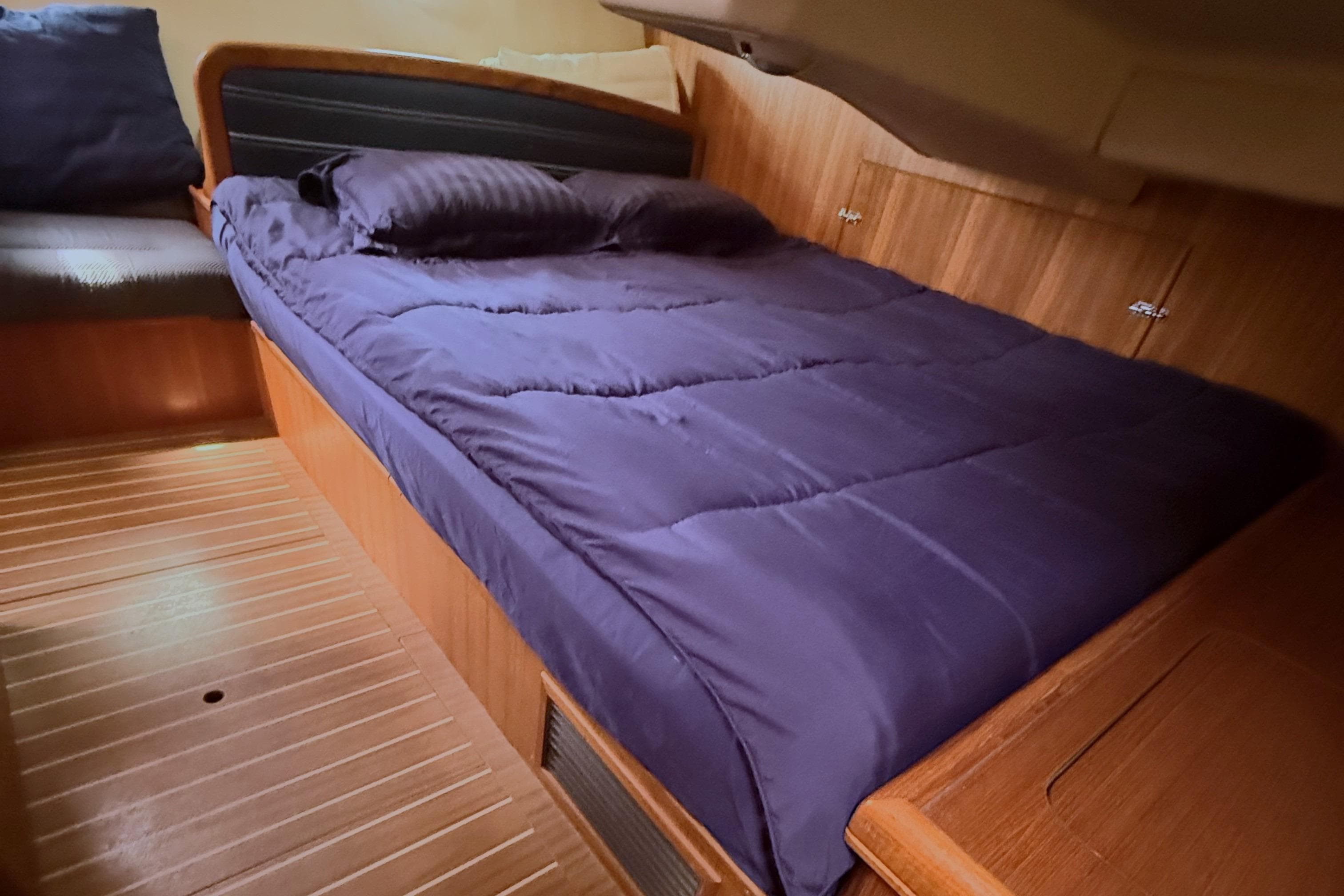 Cozy cabin interior of 2007 Hunter 38 sailboat with wooden flooring and a comfortable bed.