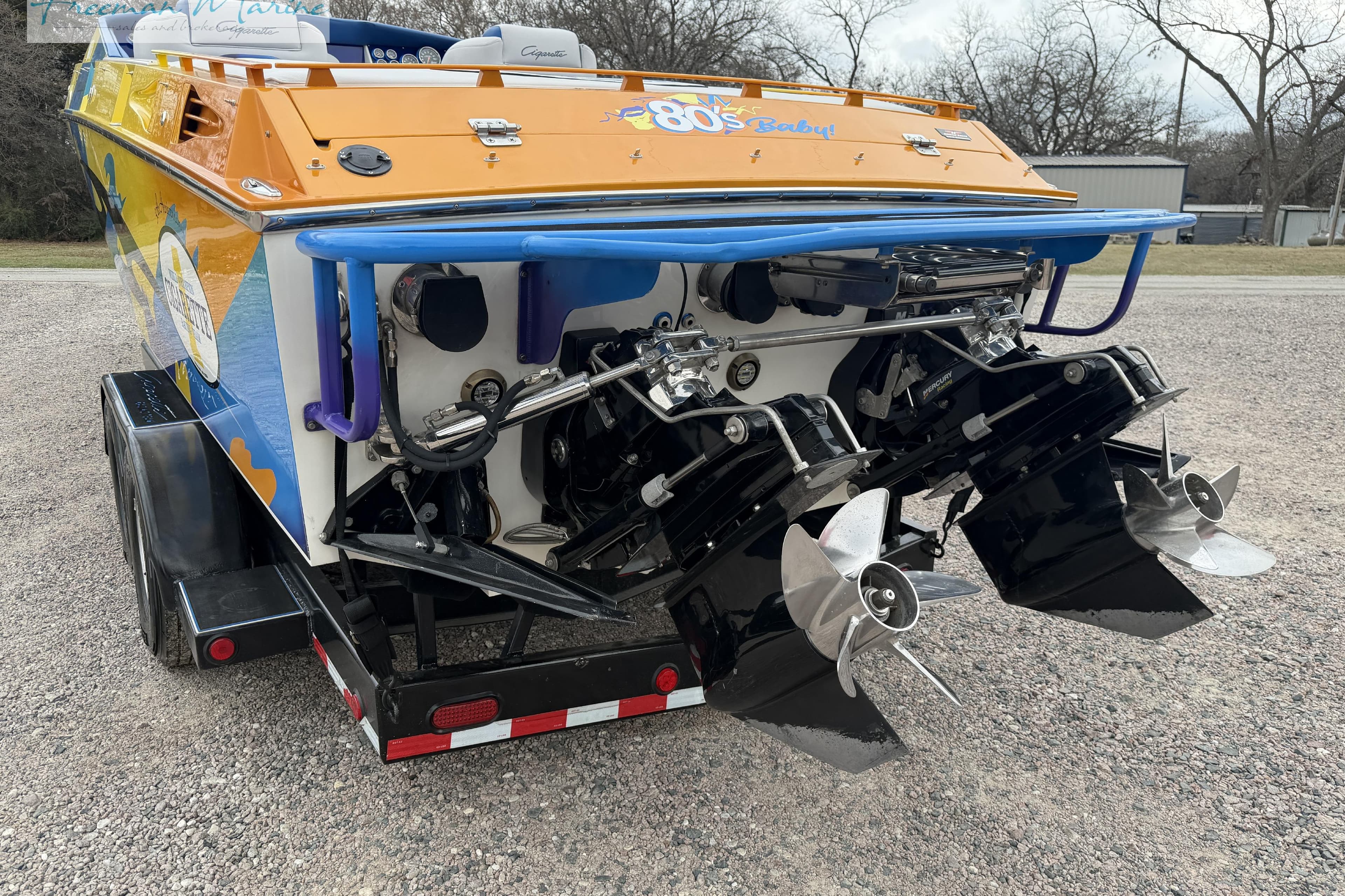 Rear view of a 2000 Cigarette 30' Mystique boat with colorful graphics and dual propellers.