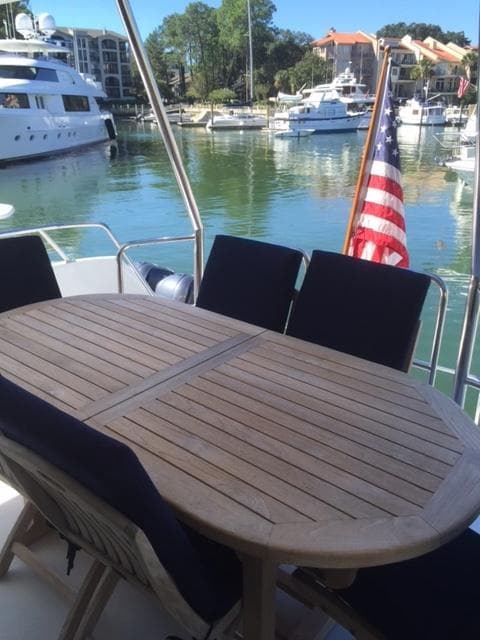 Outdoor dining area on 1998 Hatteras 74 Sport Deck yacht in marina.