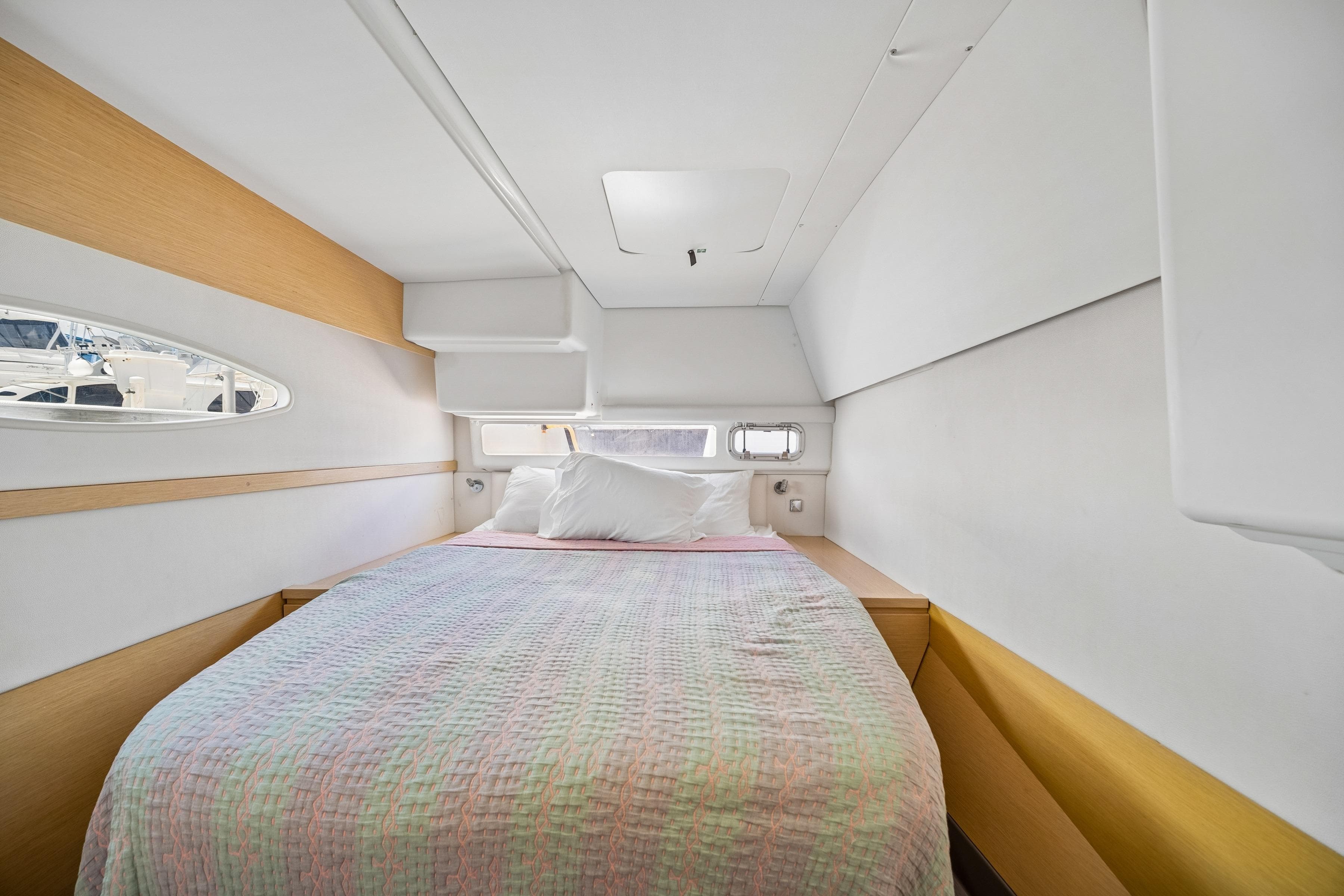 Cozy cabin interior of 2014 Fountaine Pajot Helia 44 catamaran with bed and porthole view.