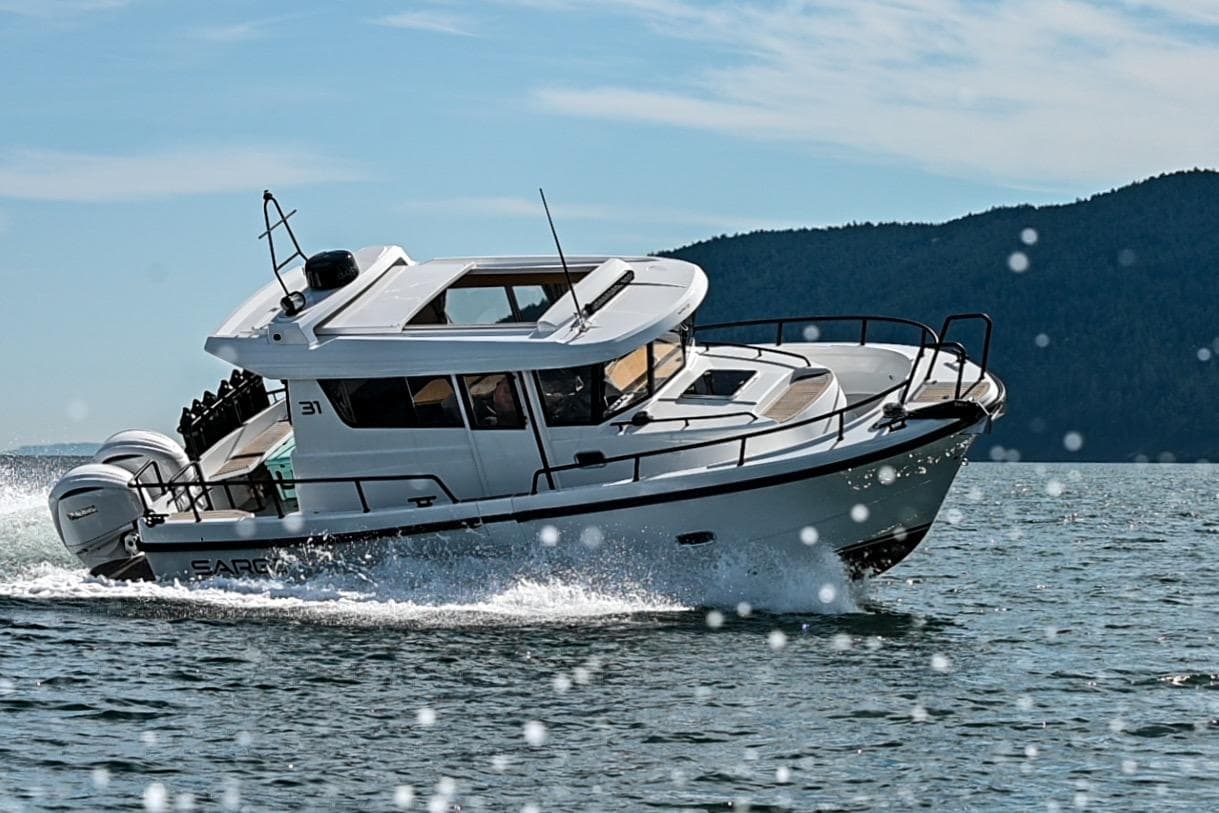 2025 Sargo 31OB boat cruising on open water with scenic mountain backdrop.