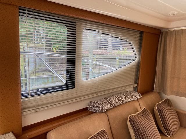 Interior of 2007 Silverton 33 Convertible yacht with window blinds and beige seating.