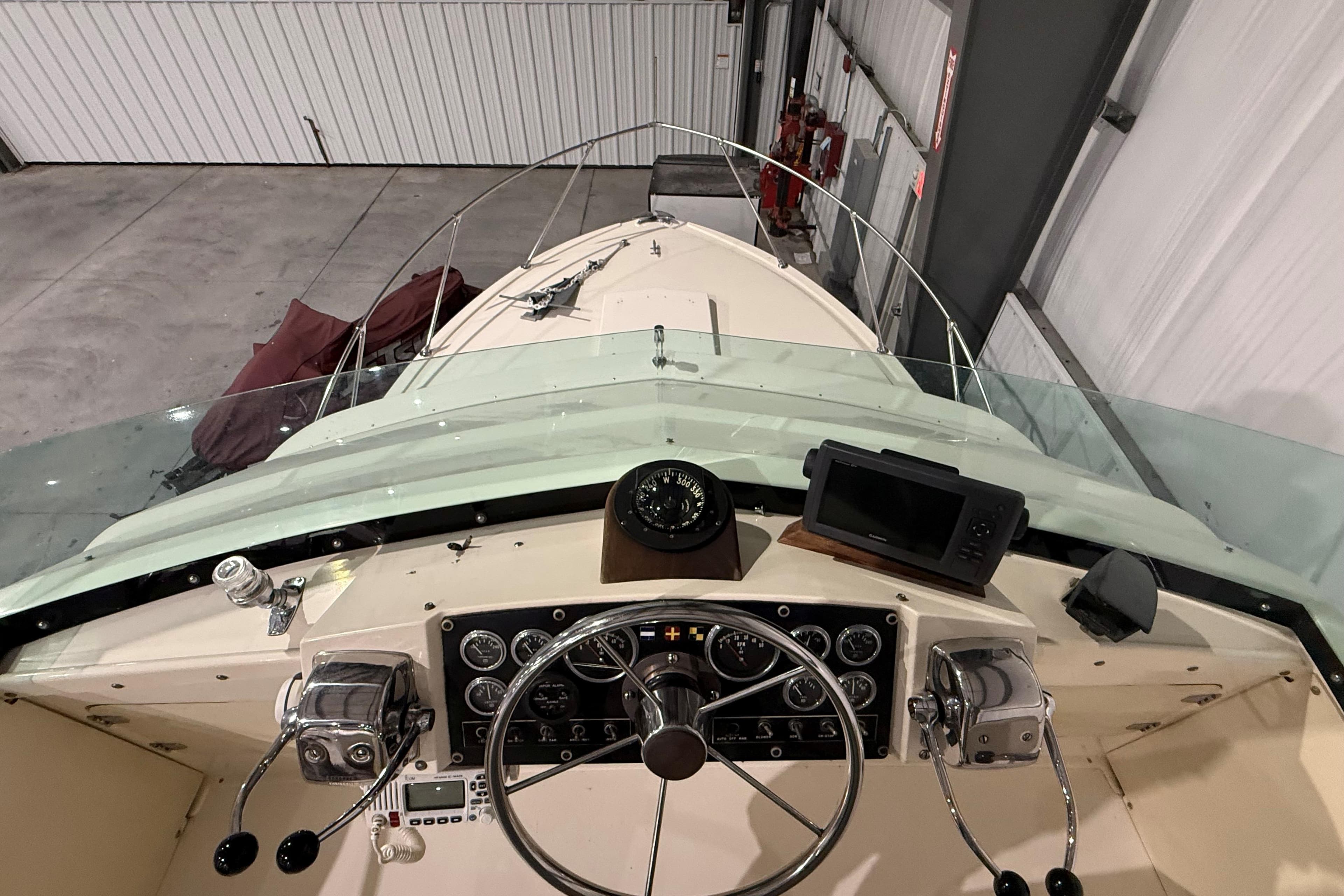 1973 Bertram 28 Flybridge Cruiser cockpit with steering wheel, compass, and navigation equipment.
