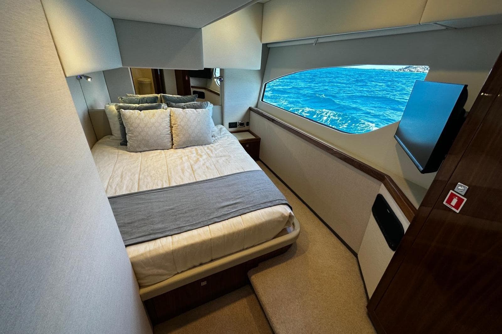 Luxurious bedroom interior of 2023 Riviera 465 SUV yacht with ocean view window.