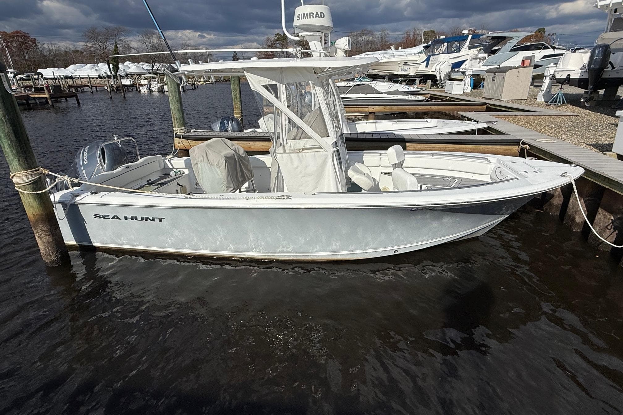 2015 Sea Hunt Ultra 234 boat docked at marina, under cloudy sky.