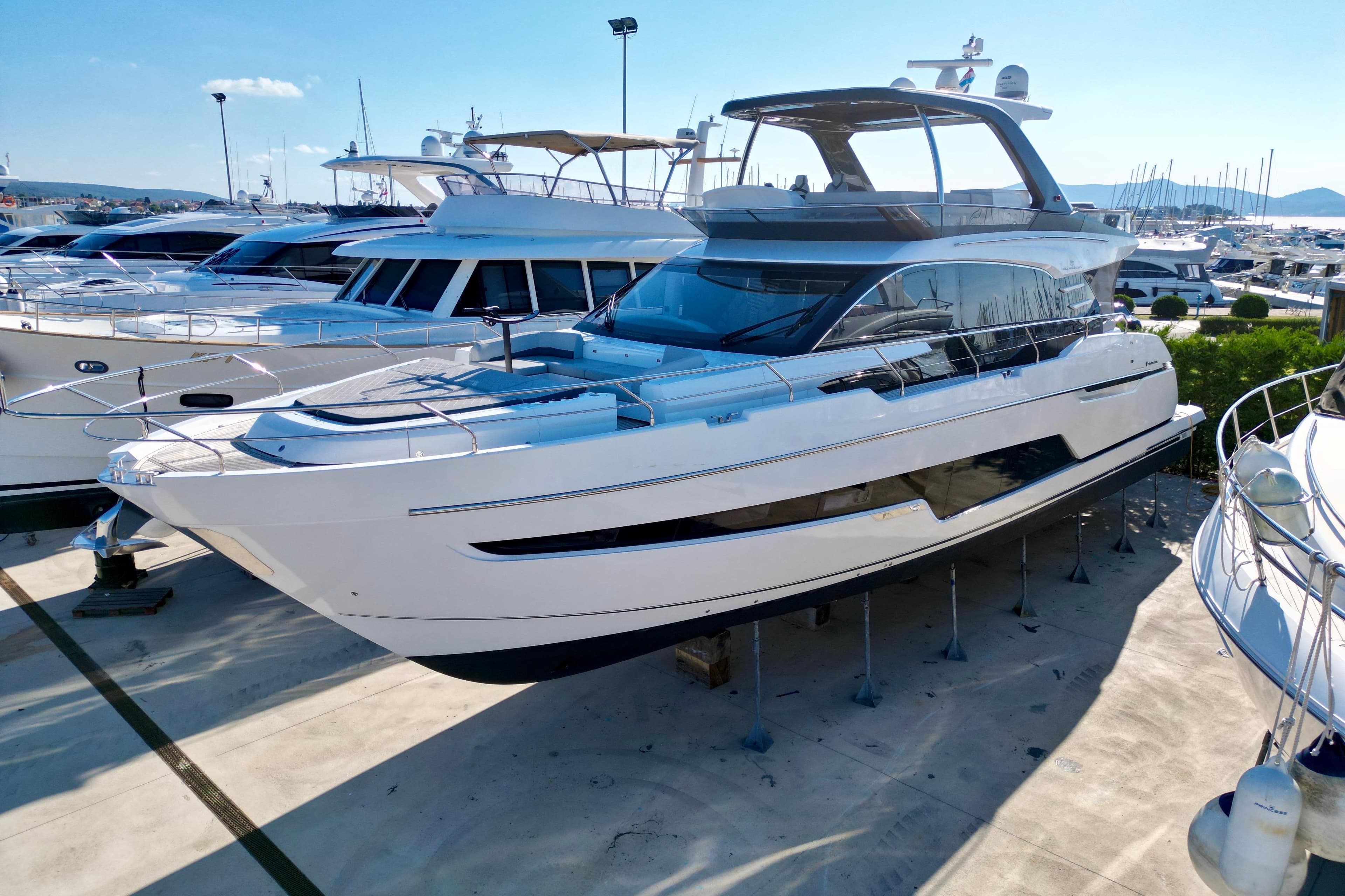 2022 Fairline Squadron 68 yacht docked in a marina under clear blue skies.