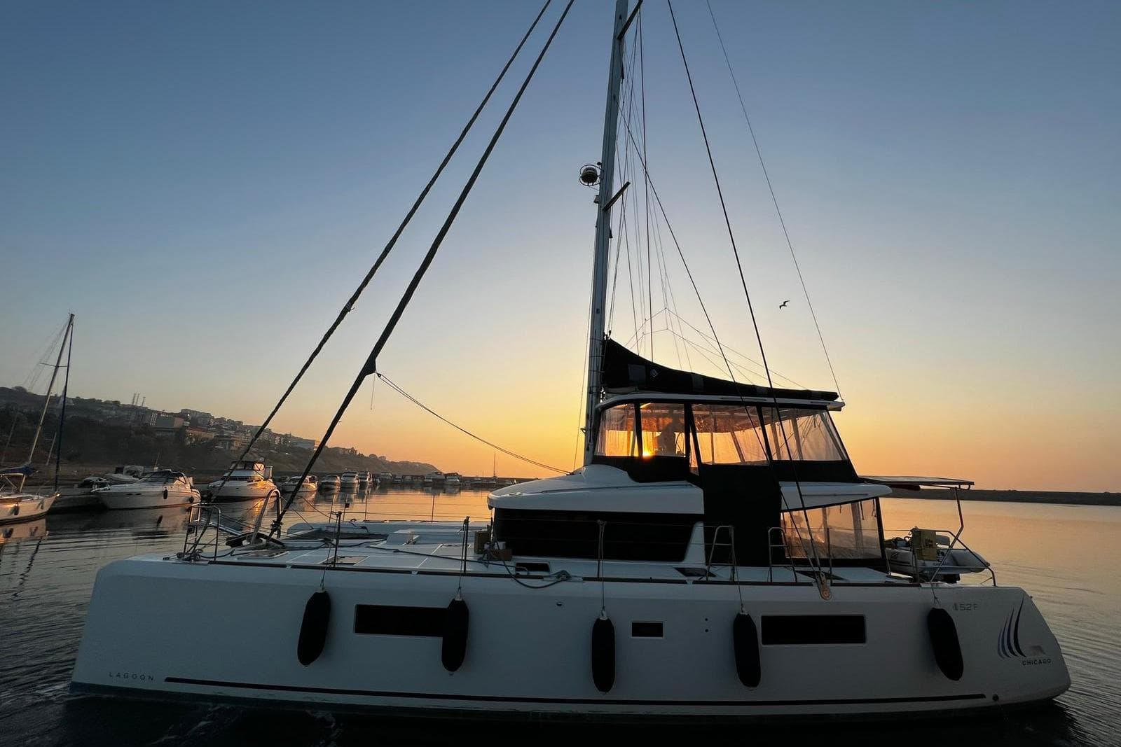 2020 Lagoon 52 F catamaran at sunset in a serene harbor setting.