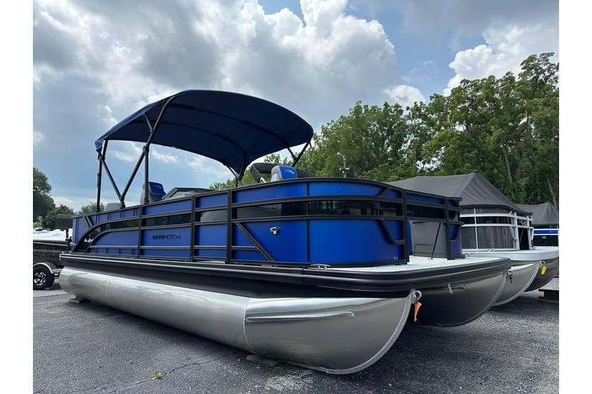 2026 Bennington 23 SF Family pontoon boat with blue canopy, parked outdoors.