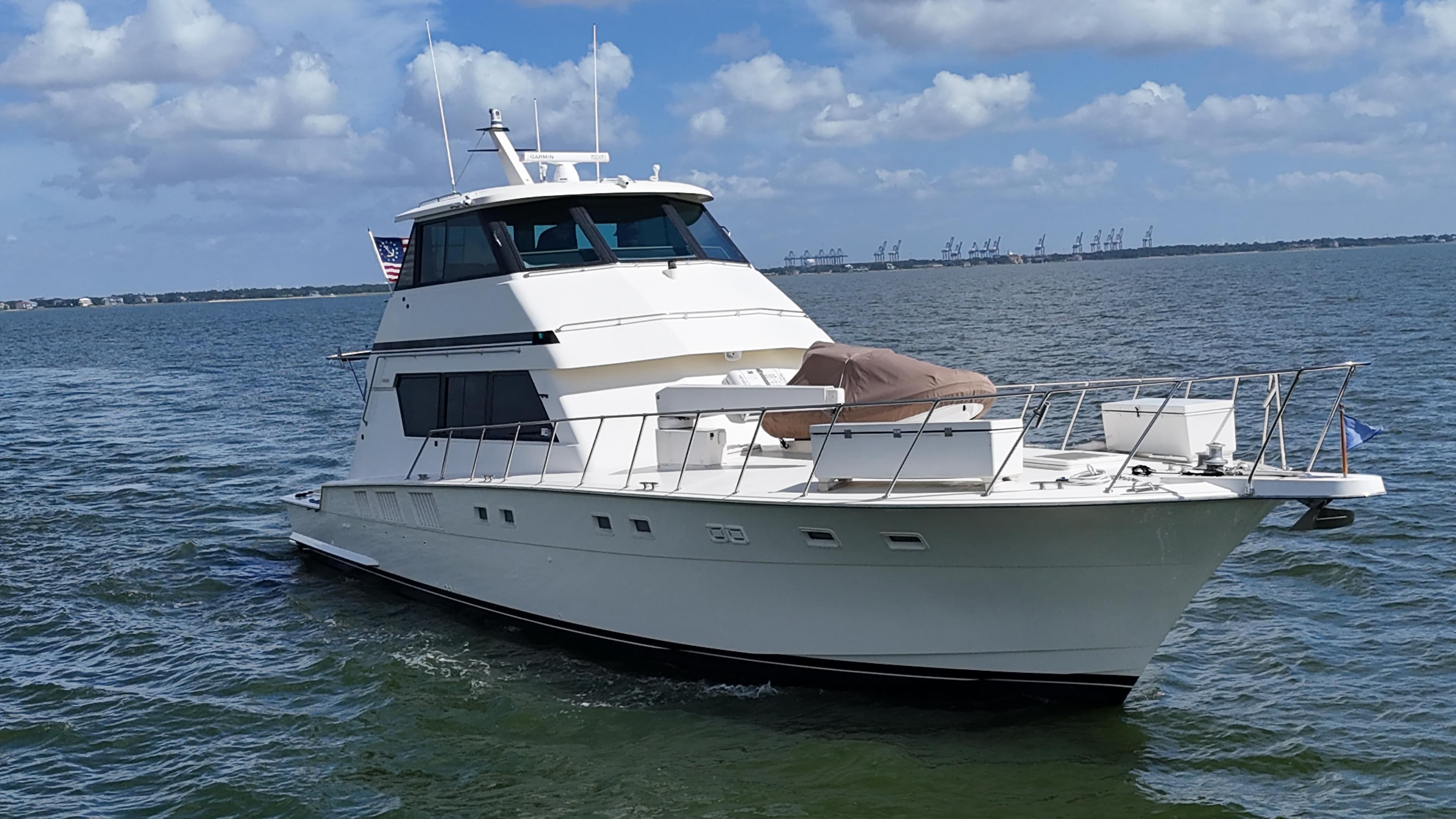 1988 Hatteras Enclosed Bridge Sportfish yacht cruising on open water under blue skies.