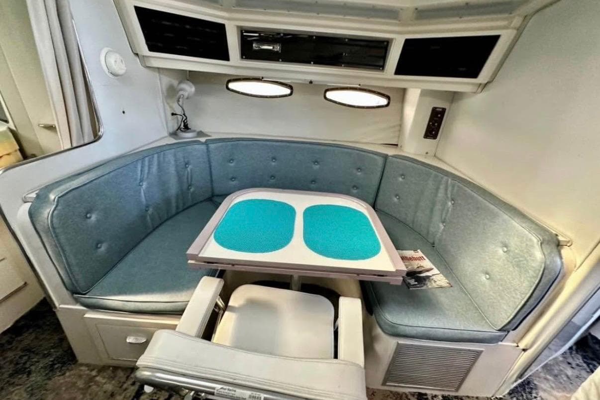 Interior of 1987 Wellcraft 3400 Gran Sport with blue cushioned seating and table.