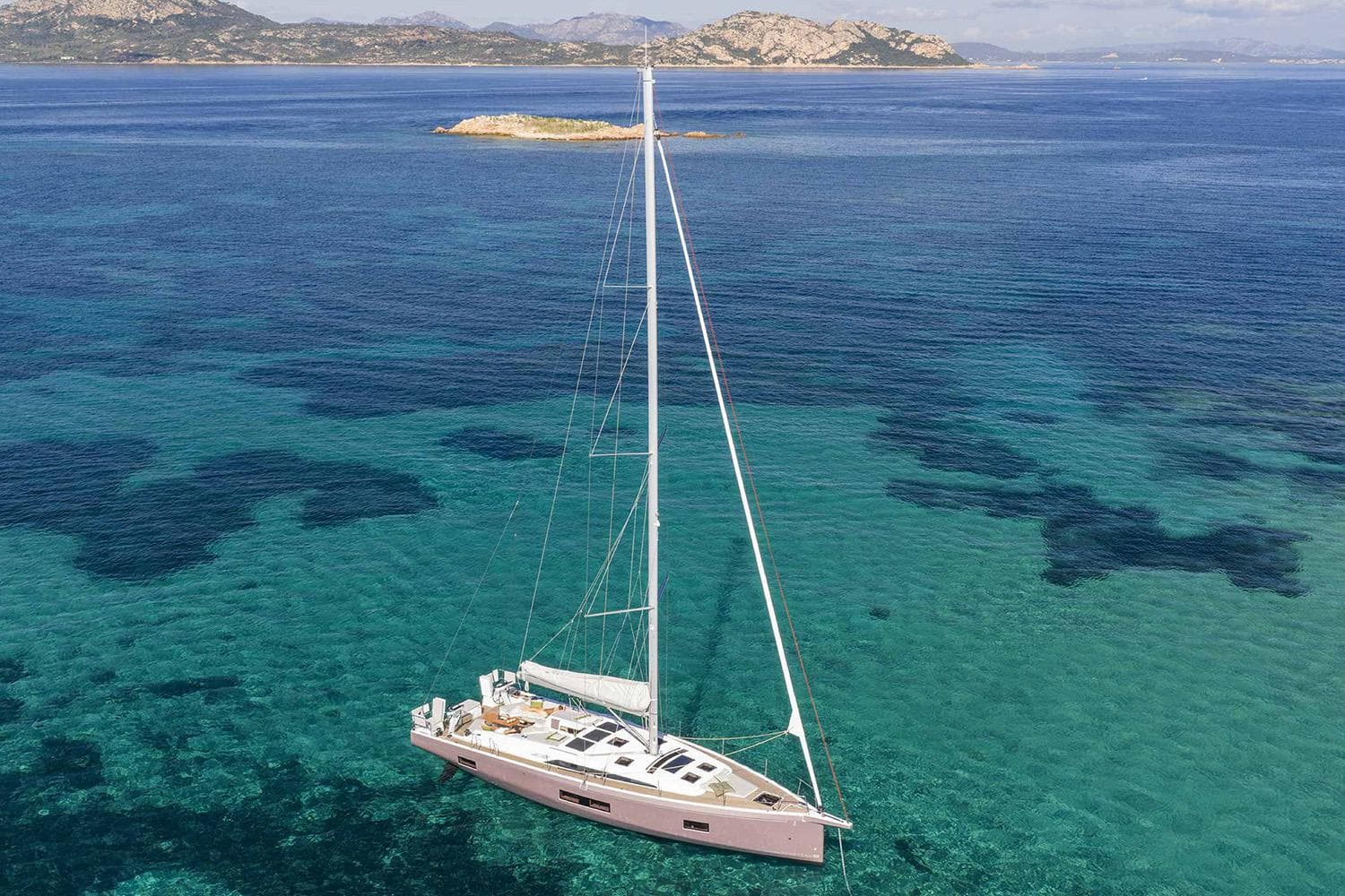 Manufacturer Provided Image: 2026 Beneteau Oceanis 52 sailing in clear turquoise waters near rocky coastline.
