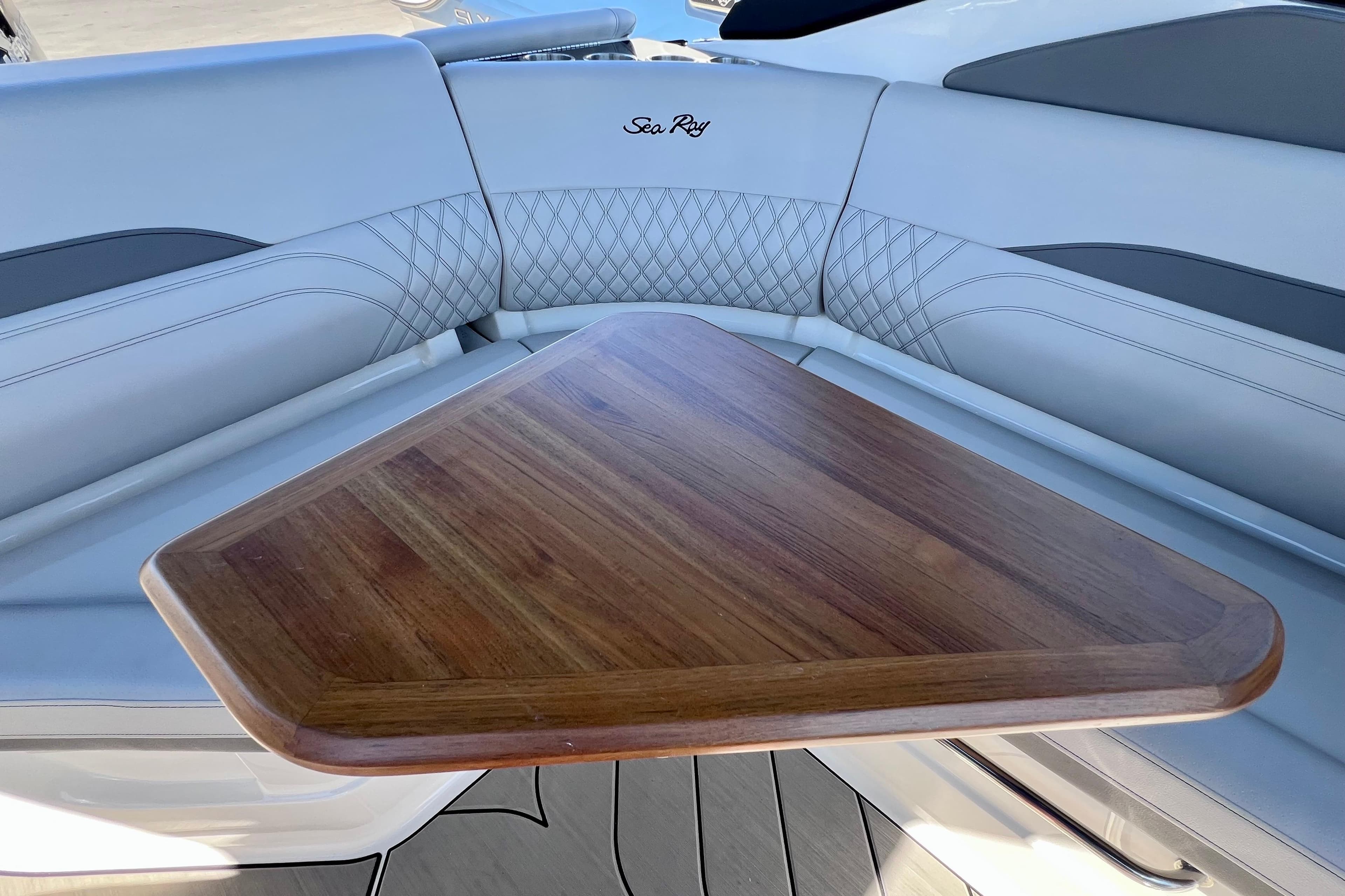 2024 Sea Ray SLX 260 Outboard interior with wooden table and cushioned seating.