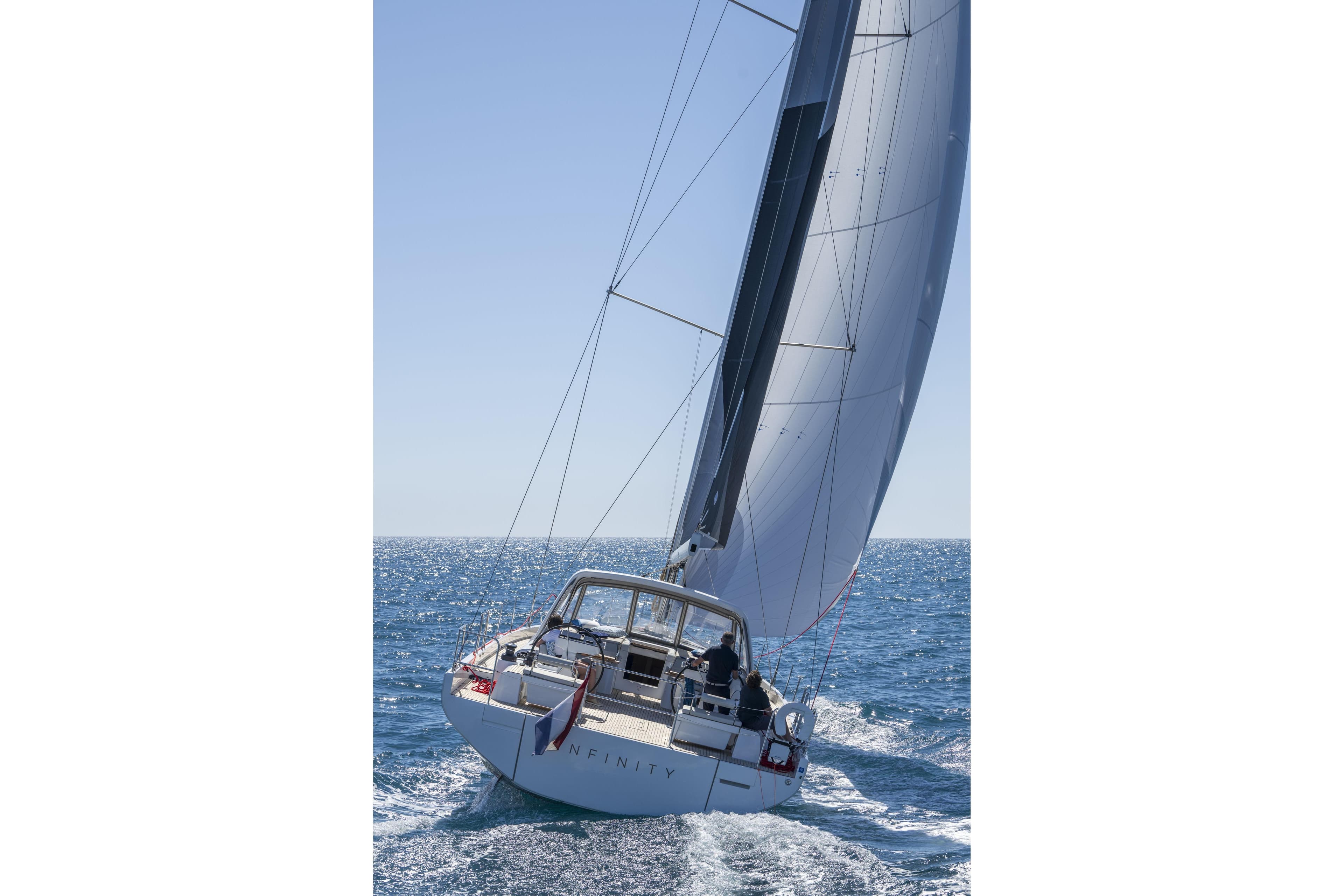 2023 Beneteau Oceanis Yacht 60 sailing on open sea under clear blue sky.