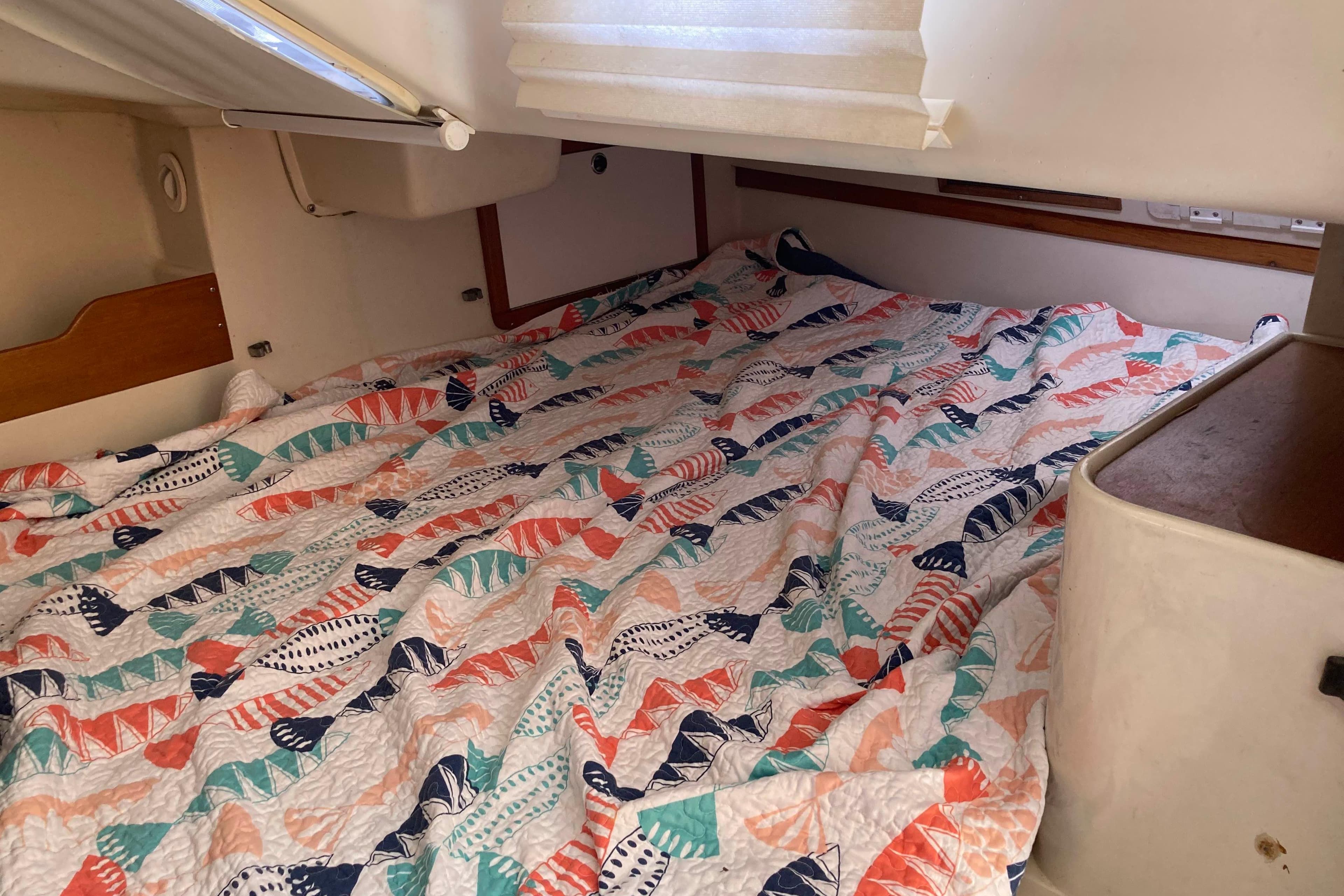 Cozy cabin interior of a 2003 Catalina 320 sailboat with colorful bedding.