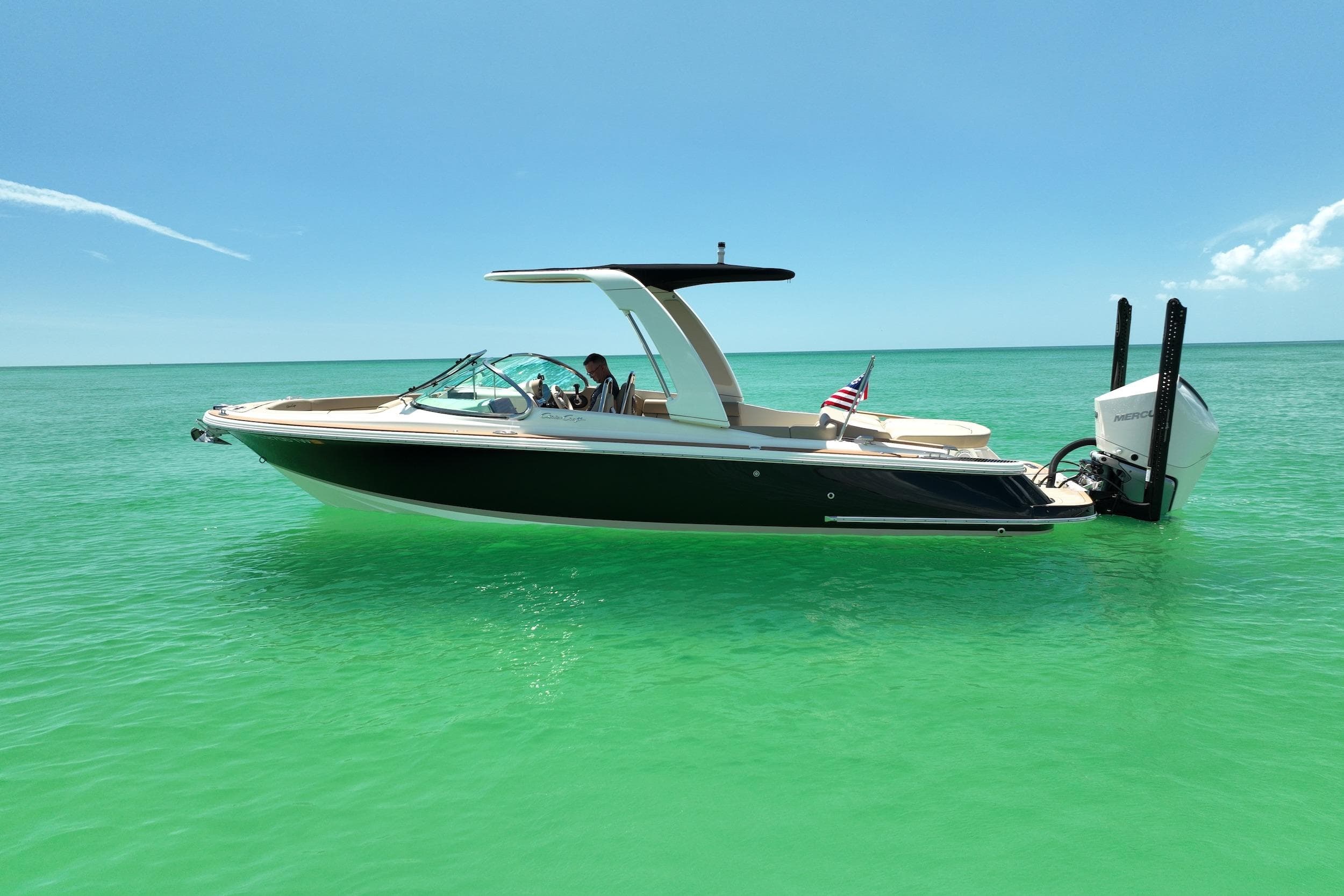 2023 Chris-Craft Launch 25 GT boat on turquoise water, clear sky background.