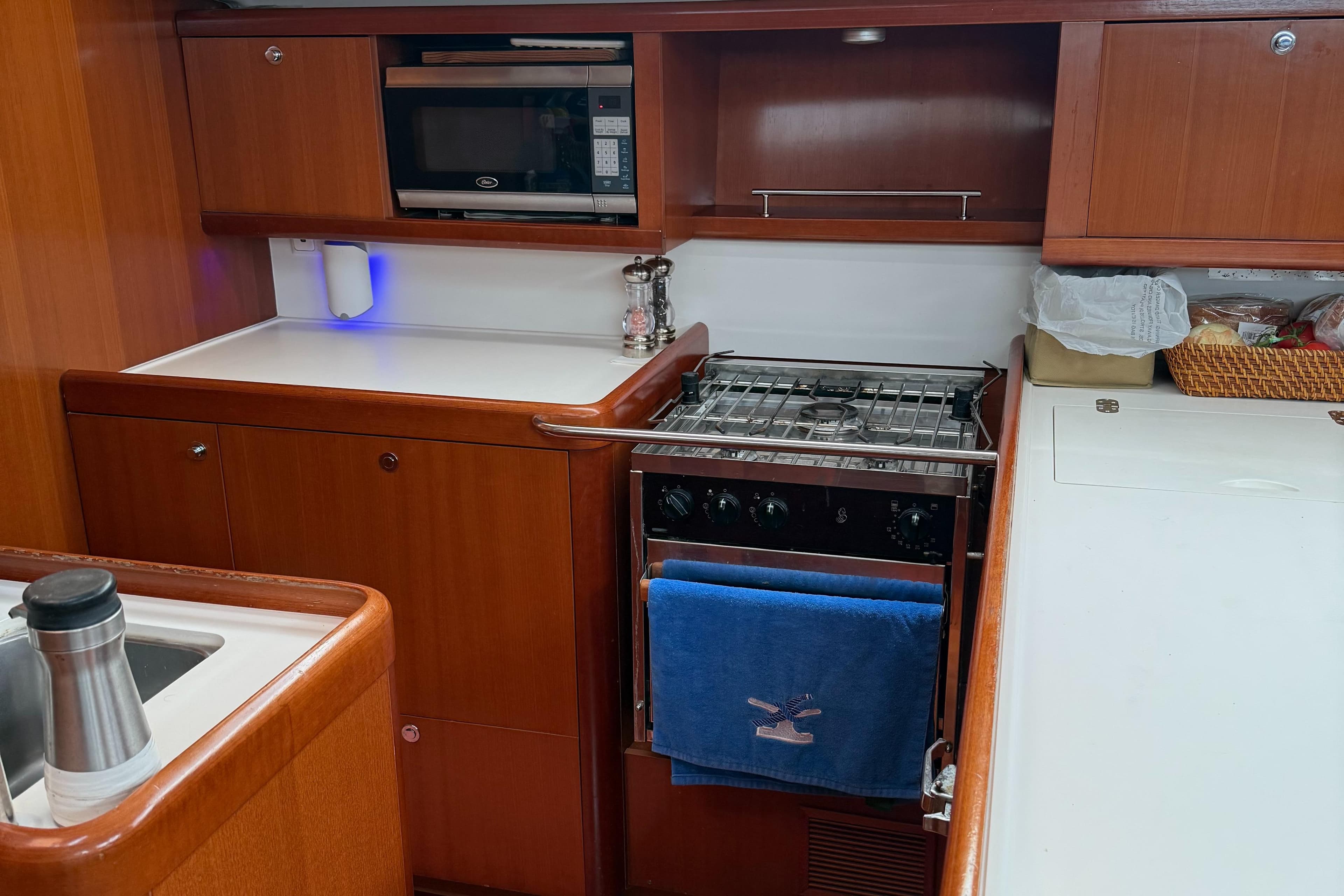 Galley kitchen in 2007 Beneteau 49 yacht with stove, microwave, and wooden cabinetry.