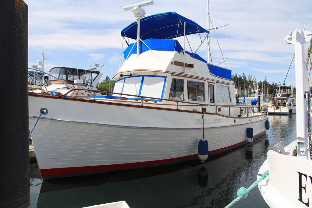 1974 Grand Banks 42 Motoryacht docked, featuring classic design and blue canopy.