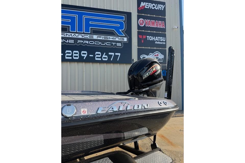2025 Falcon Boats F21 Predator with outboard motor, displayed outside a marine products store.