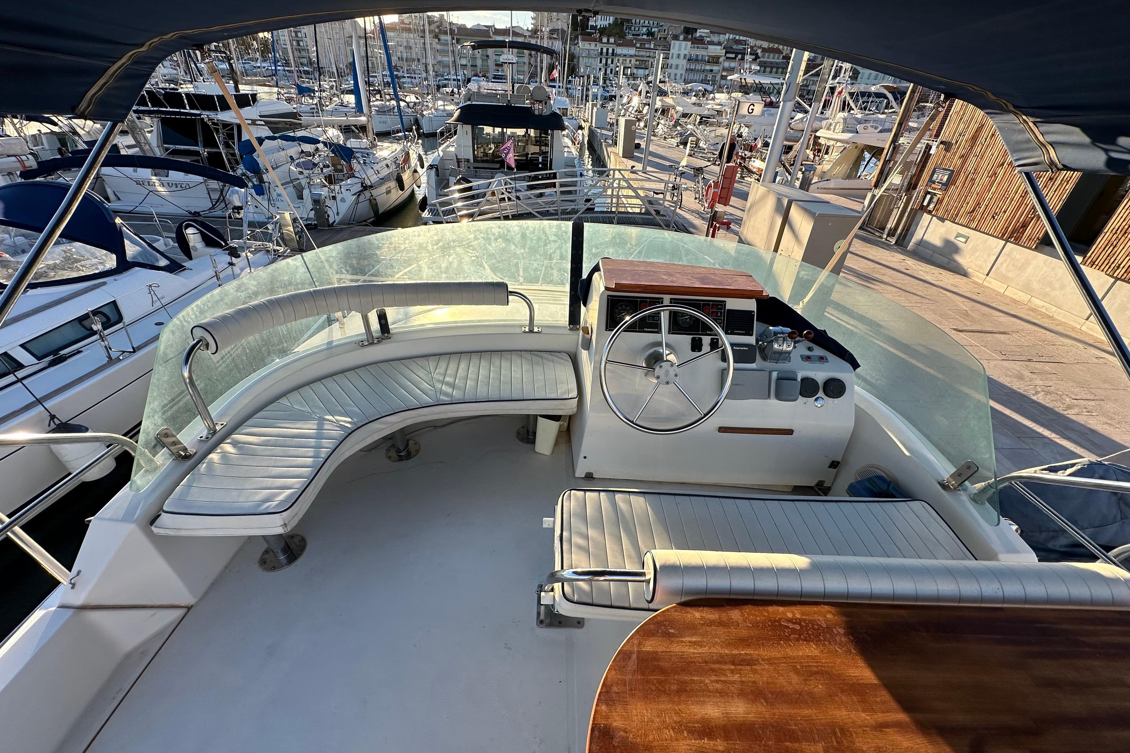 Flybridge of 1999 Fountaine Pajot Maryland 37 yacht docked at marina, featuring helm and seating.