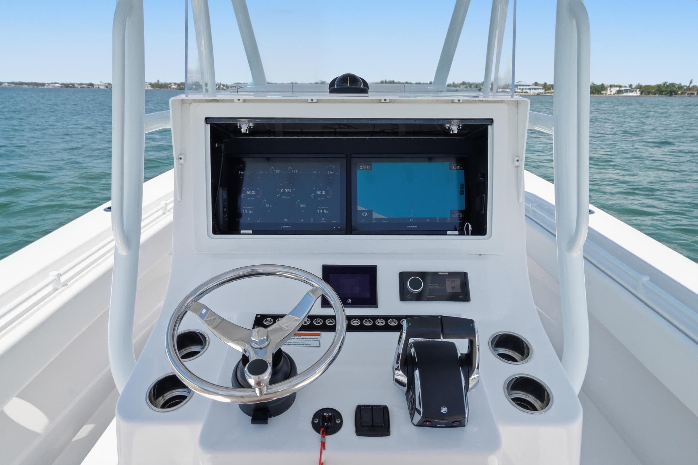 2024 Contender 32 ST boat dashboard with steering wheel and navigation screens on open water.