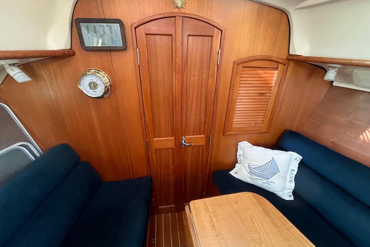 Interior of 2002 Hunter 326 sailboat with wooden paneling and navy seating.