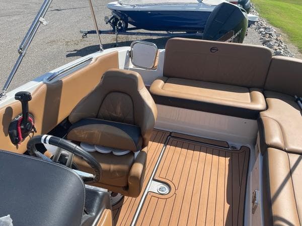 2023 Crownline E225 XS boat interior with tan seating and wood-style flooring.