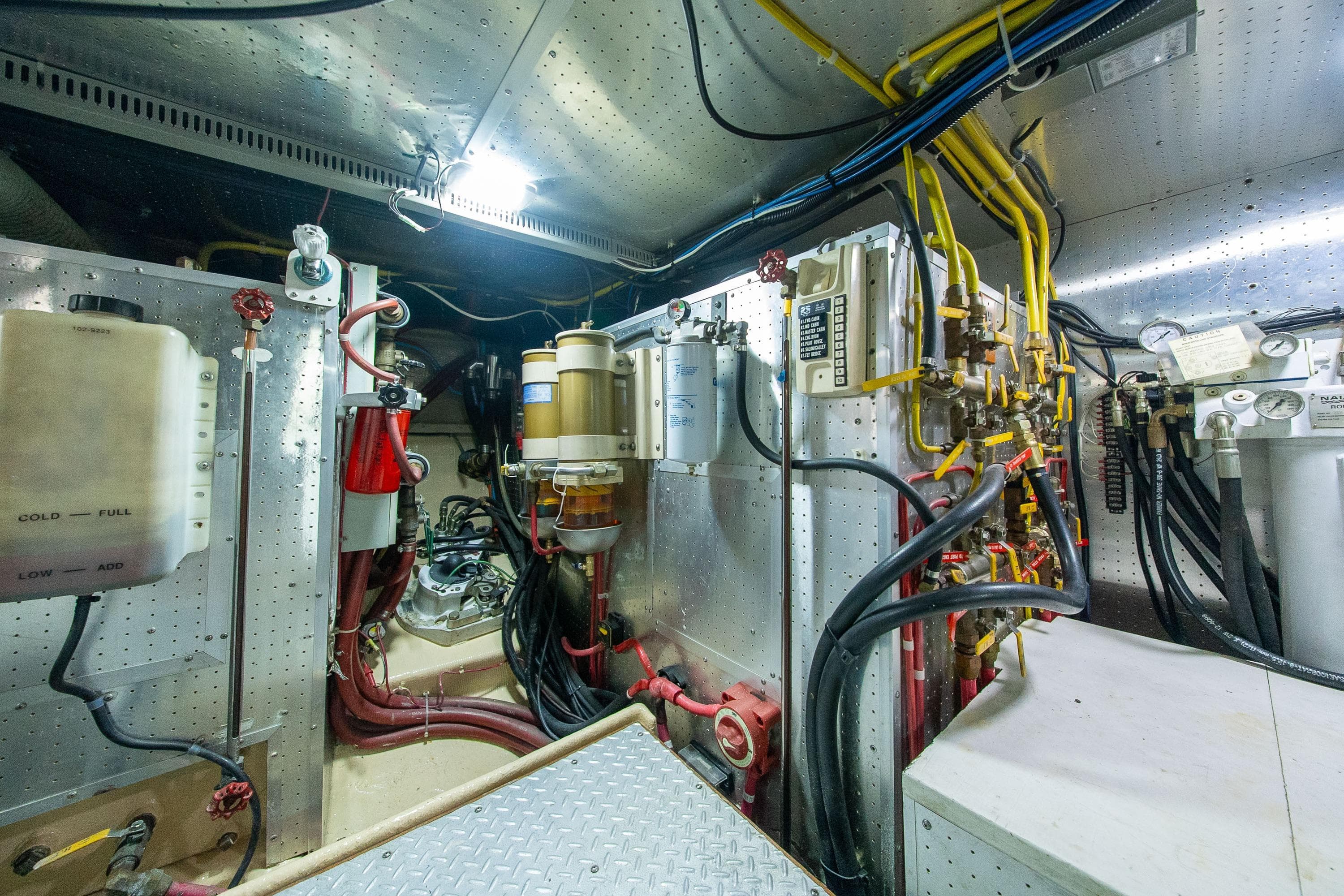 Engine room of a 2000 Grand Alaskan Pilothouse Trawler, showcasing complex machinery and wiring.