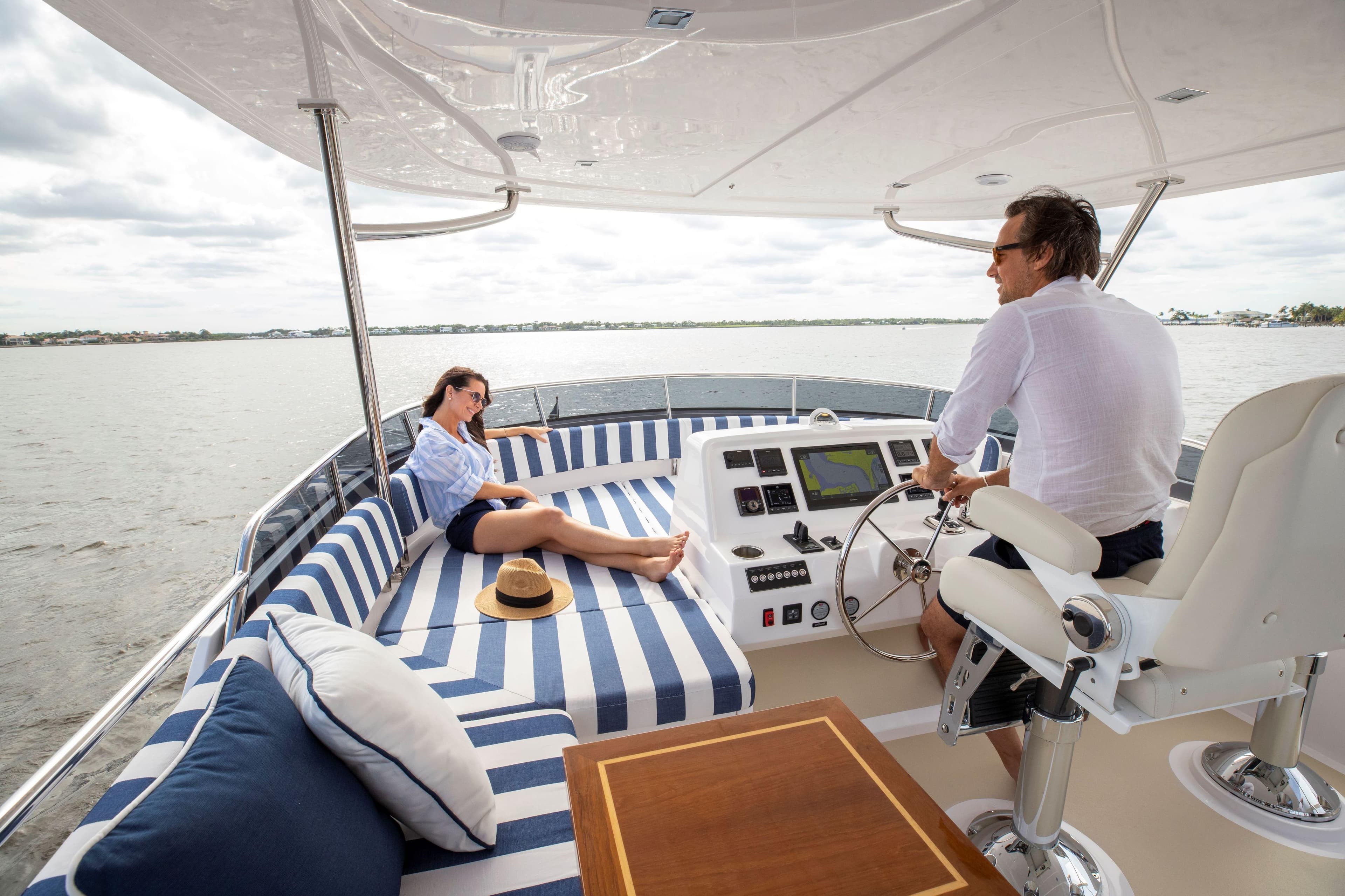 Couple enjoying a day on a 2025 Summit 54 yacht, relaxing on striped cushions.