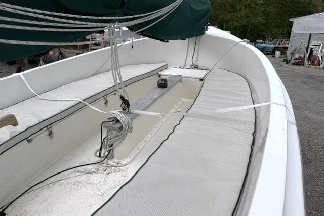 2019 Com-Pac Picnic Cat sailboat with green canopy, docked outdoors.