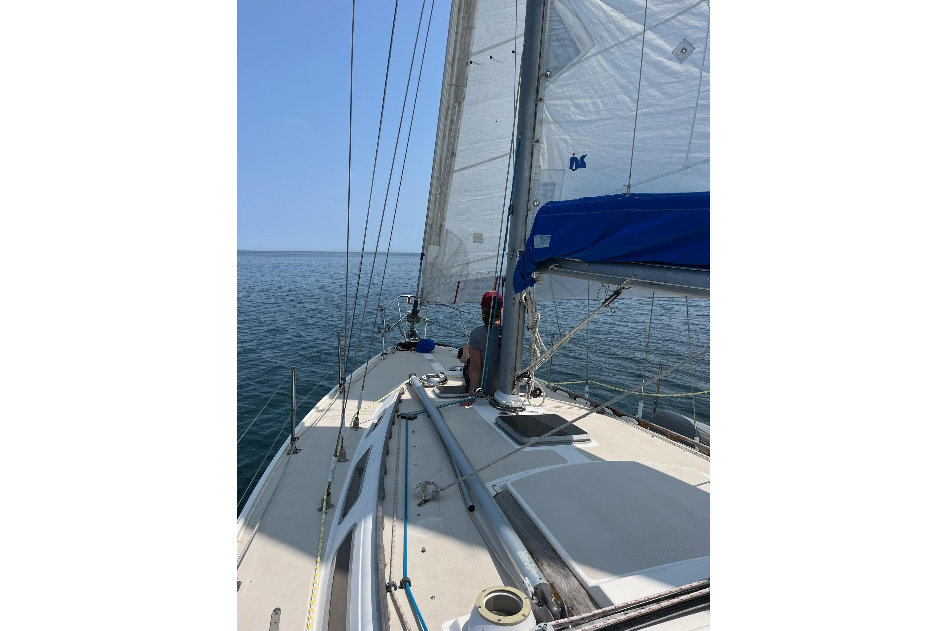 1985 Catalina 36 sailboat on calm ocean waters under clear blue sky.