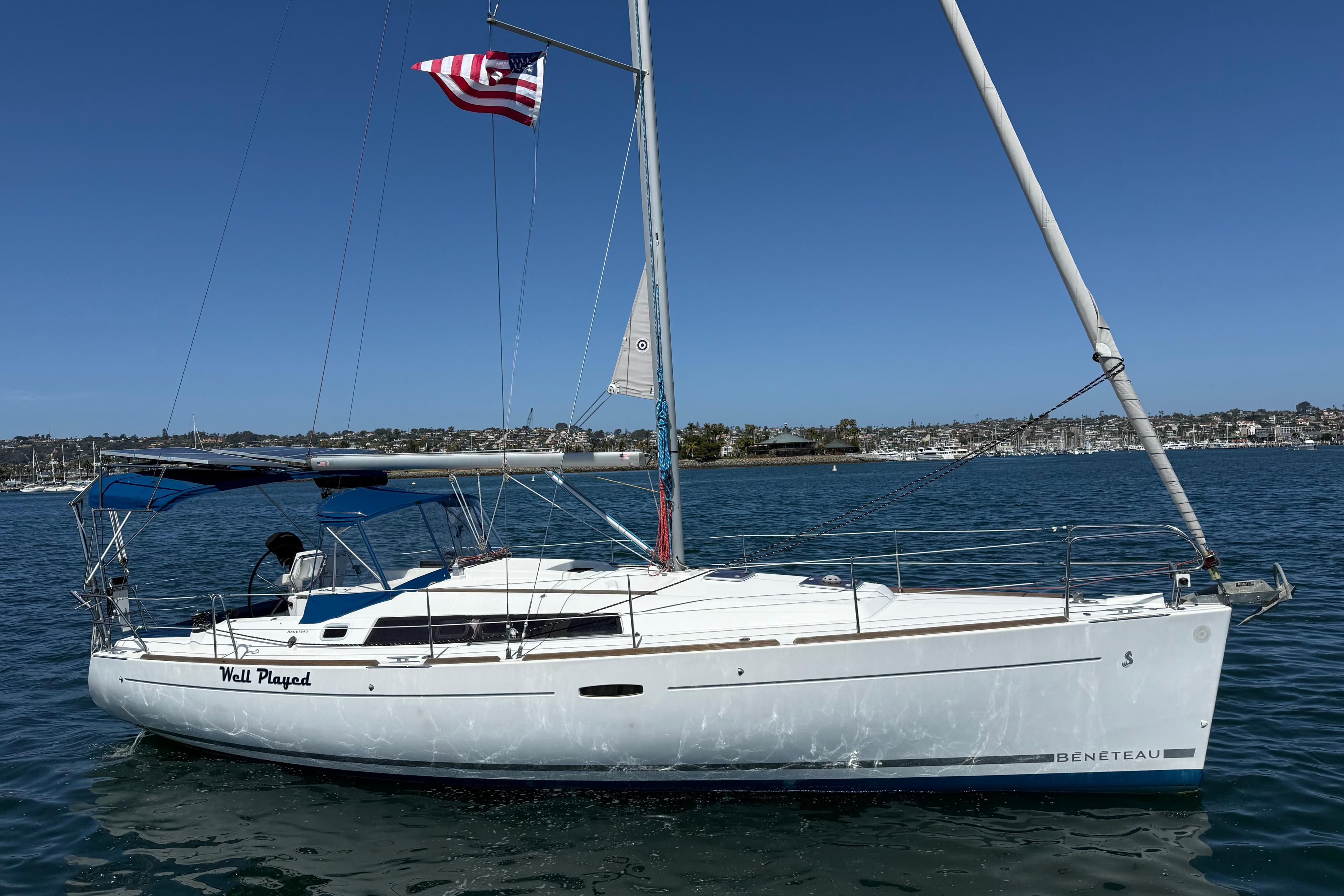 2012 Beneteau Oceanis 37 sailboat on water, flying American flag, clear sky background.