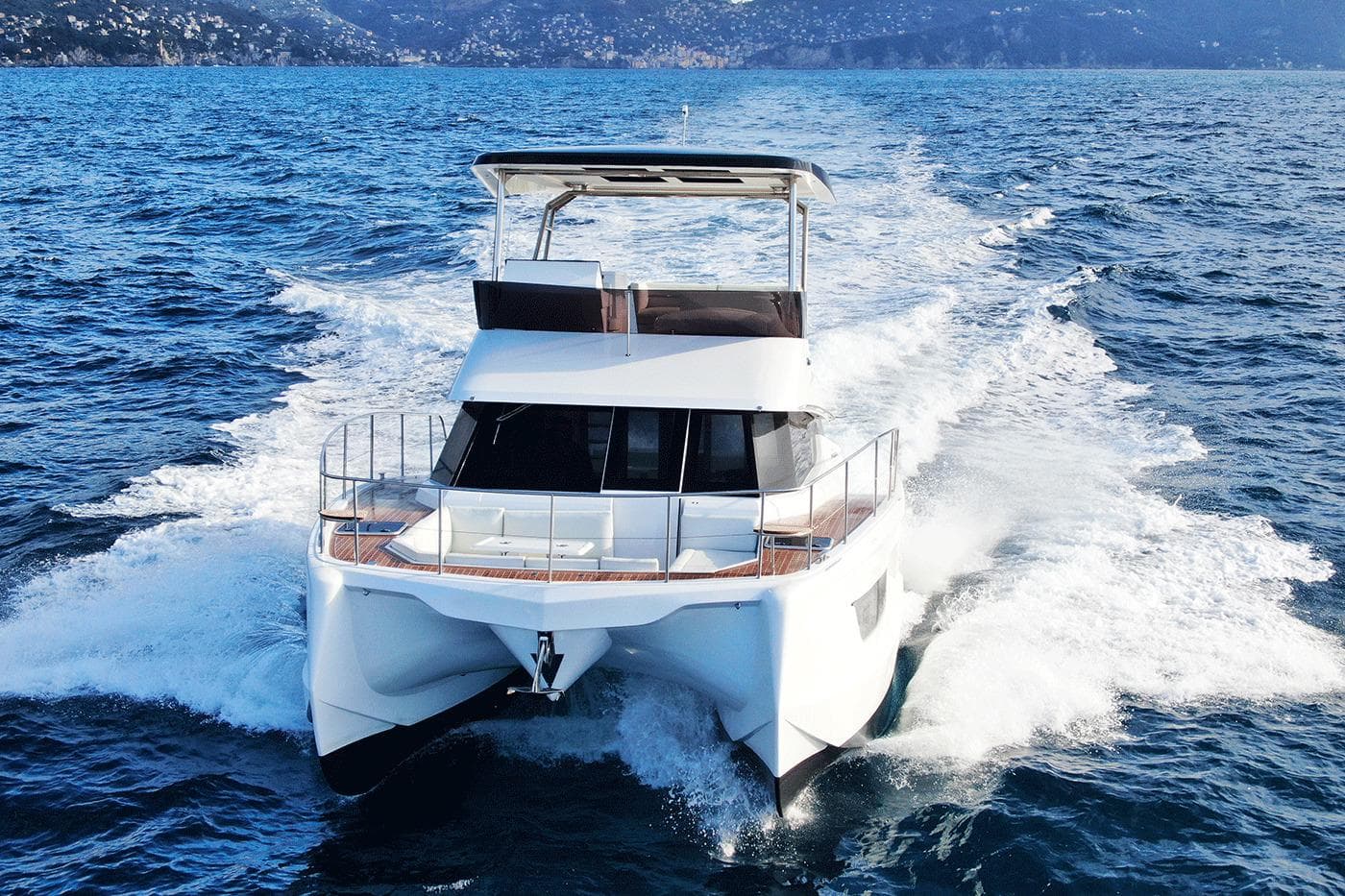 2026 Aventura 38 Motor Yacht cruising on open sea with scenic mountain backdrop.