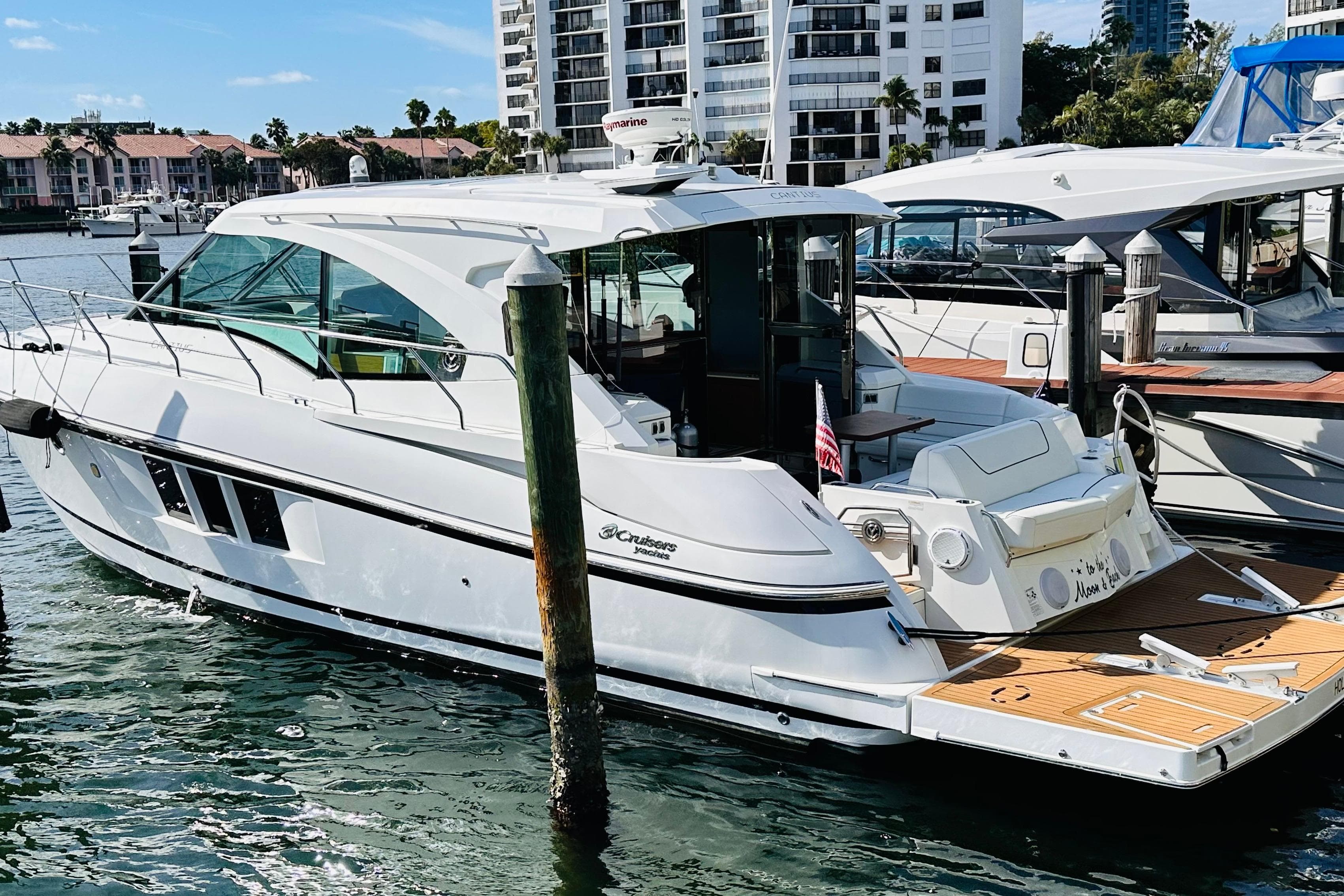 2014 Cruisers Yachts 45 Cantius docked in a marina, surrounded by water and buildings.