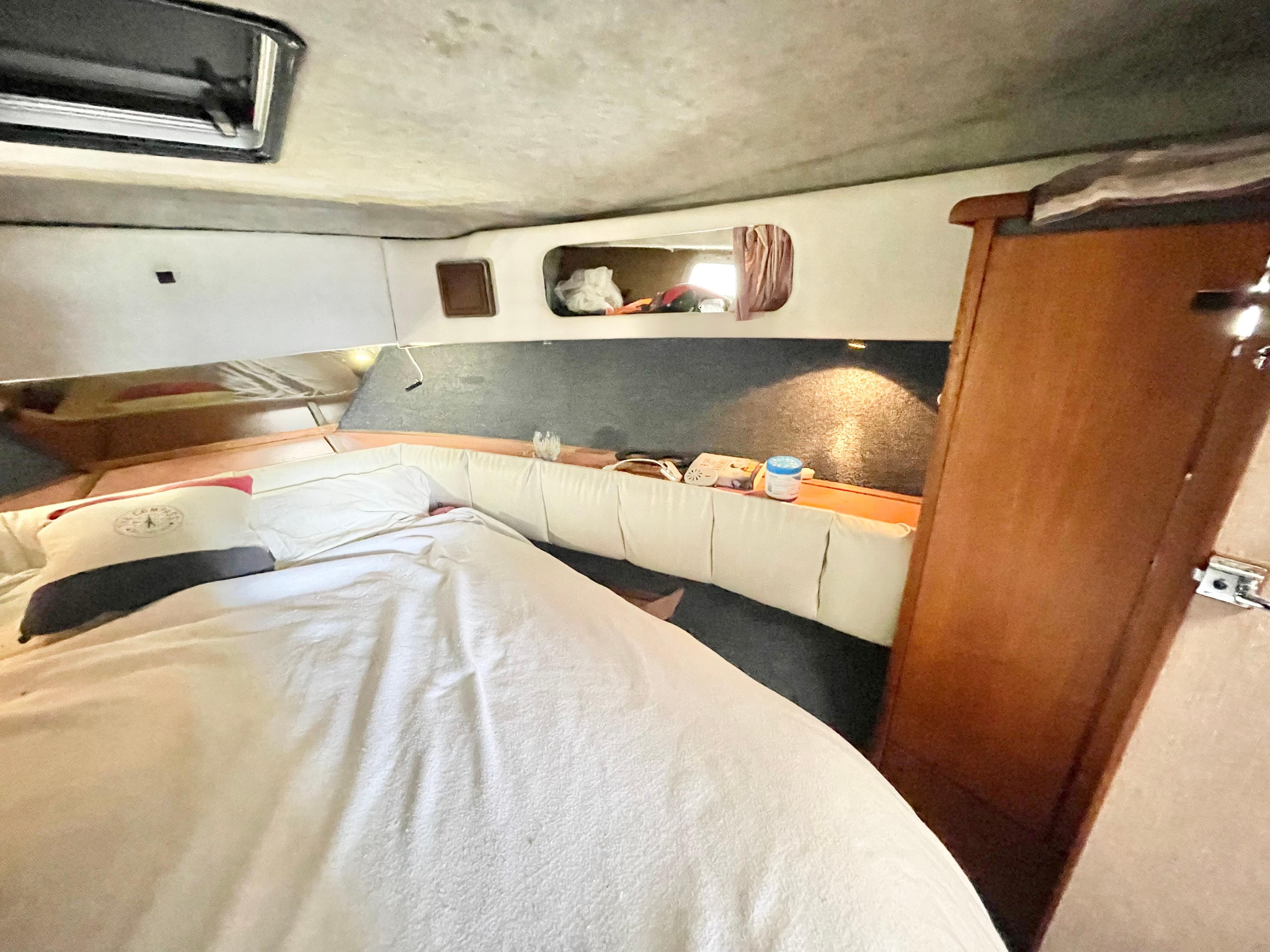 1987 Bayliner 3870 Motoryacht cabin interior with bed, wooden storage, and cozy decor.
