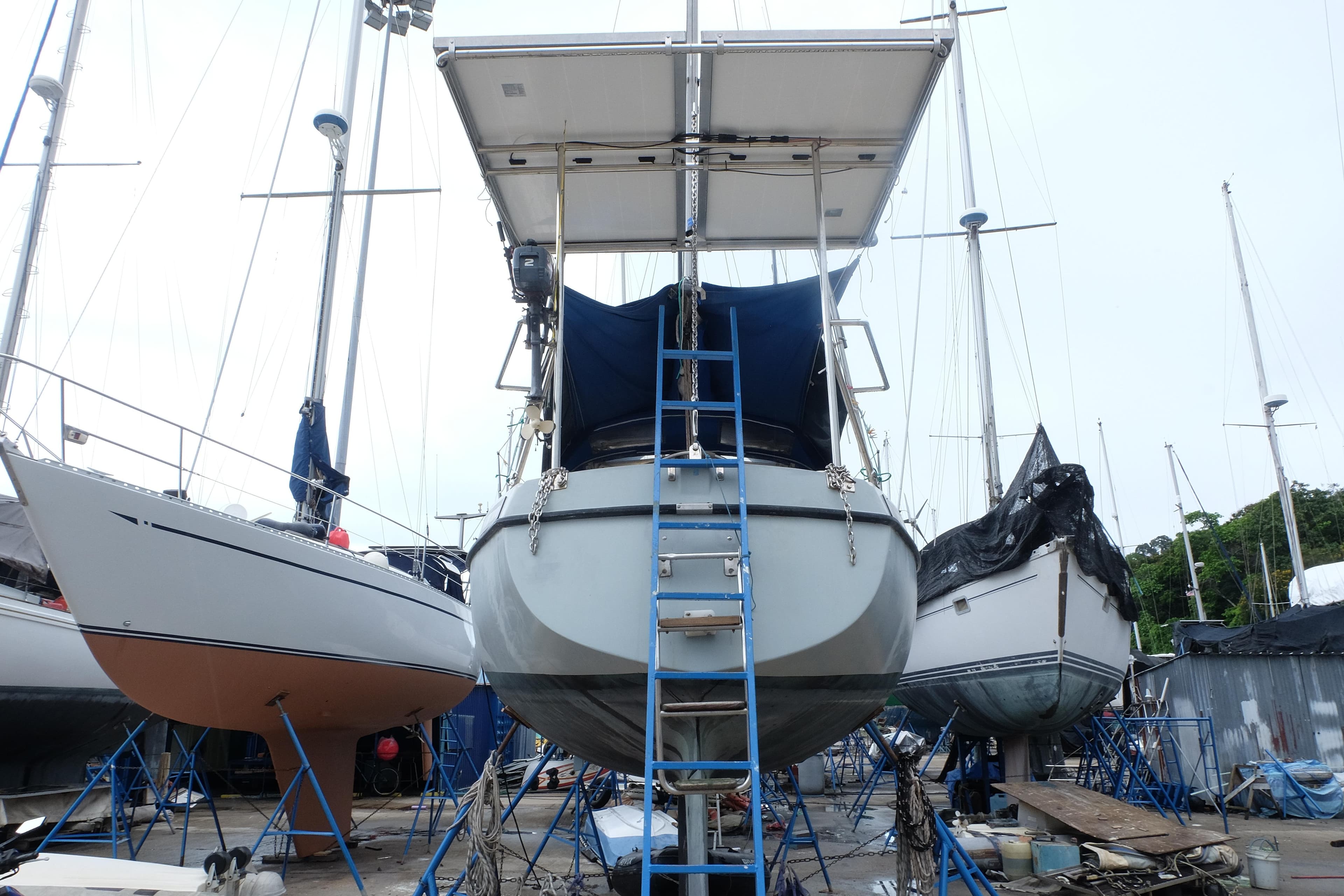 1983 Maxi 100 PS sailboat on stands in a boatyard, surrounded by other vessels.