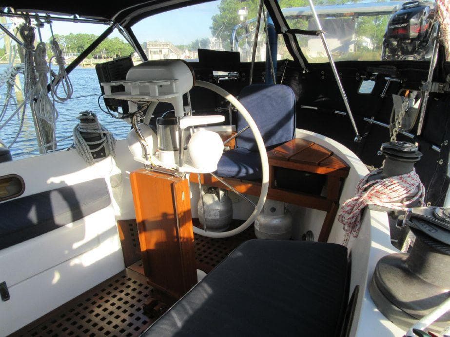 1981 Southern Cross 39' sailboat cockpit with steering wheel and seating, docked by the water.