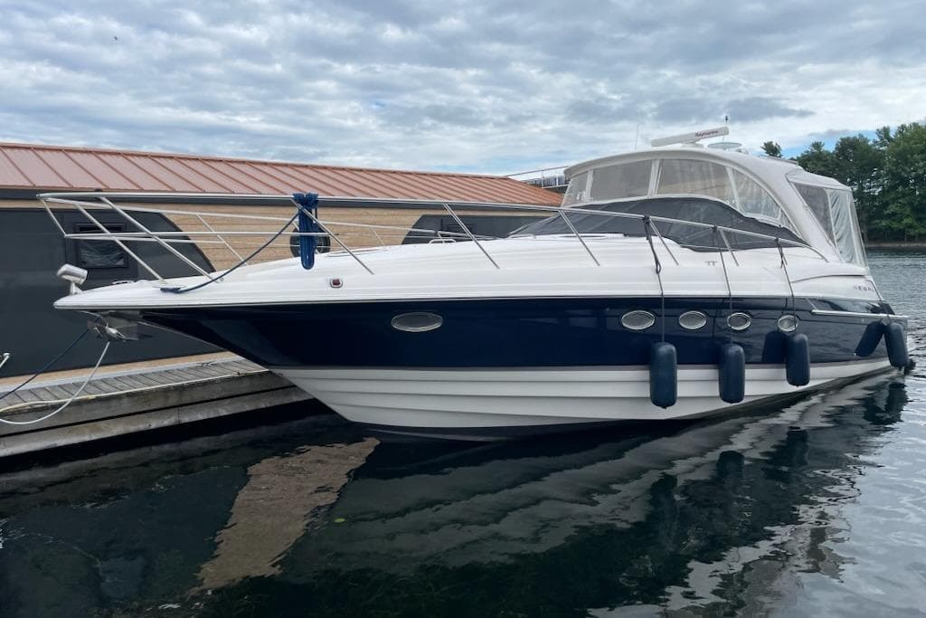 2004 Regal Commodore 4260 yacht docked, featuring sleek design and blue accents under cloudy skies.