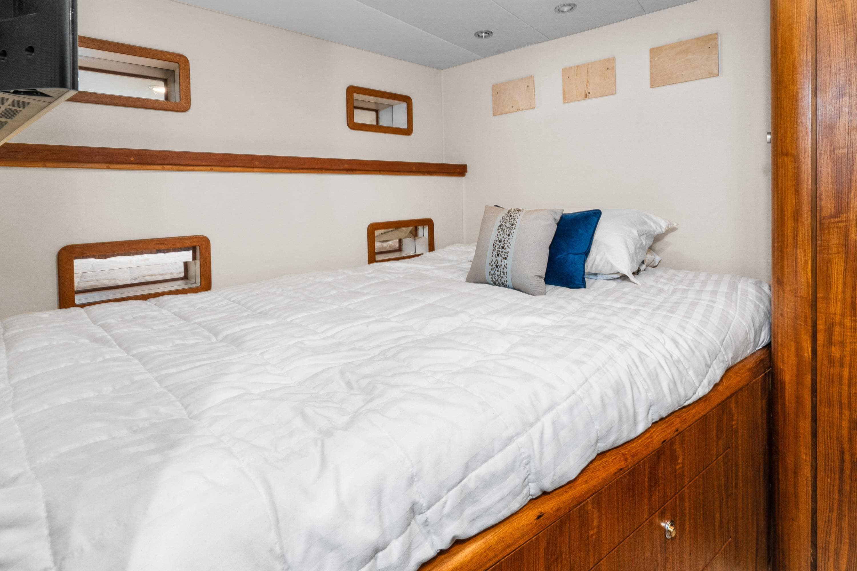 Cozy bedroom interior in 1998 Northern Marine Trawler with wooden accents and plush bedding.