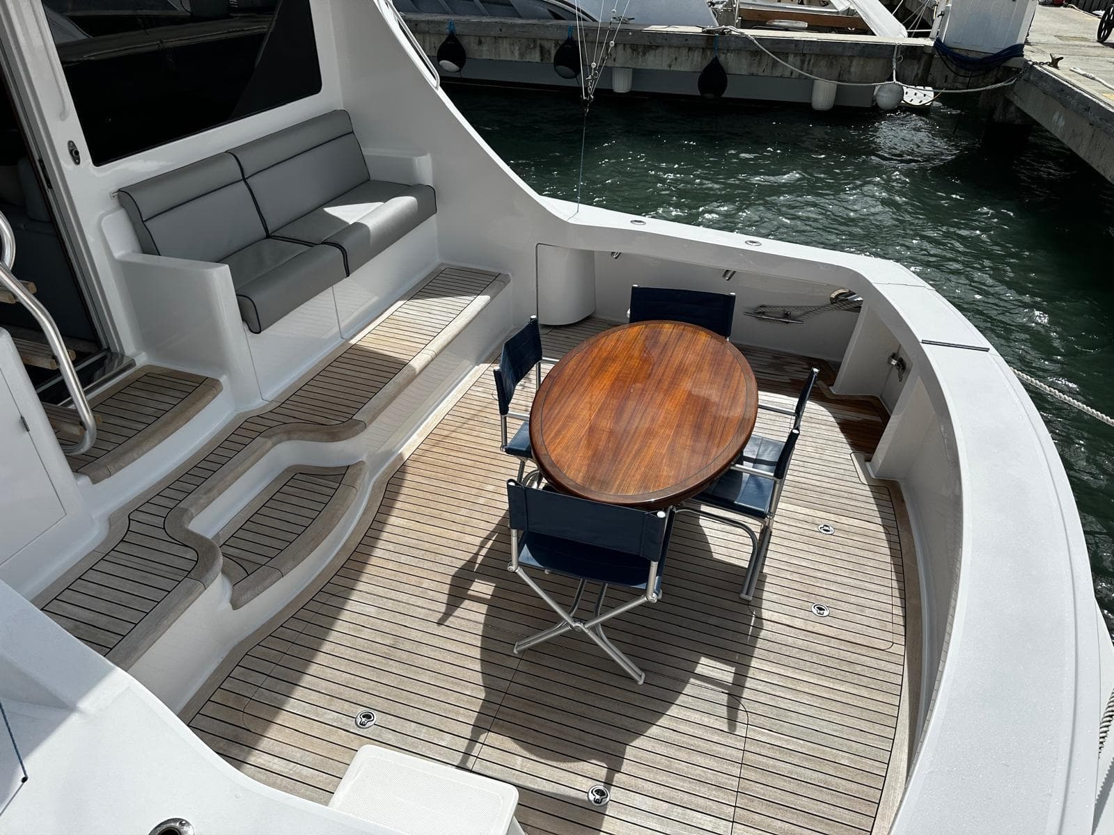 2011 Hatteras GT60 yacht deck with seating and wooden table, docked at marina.
