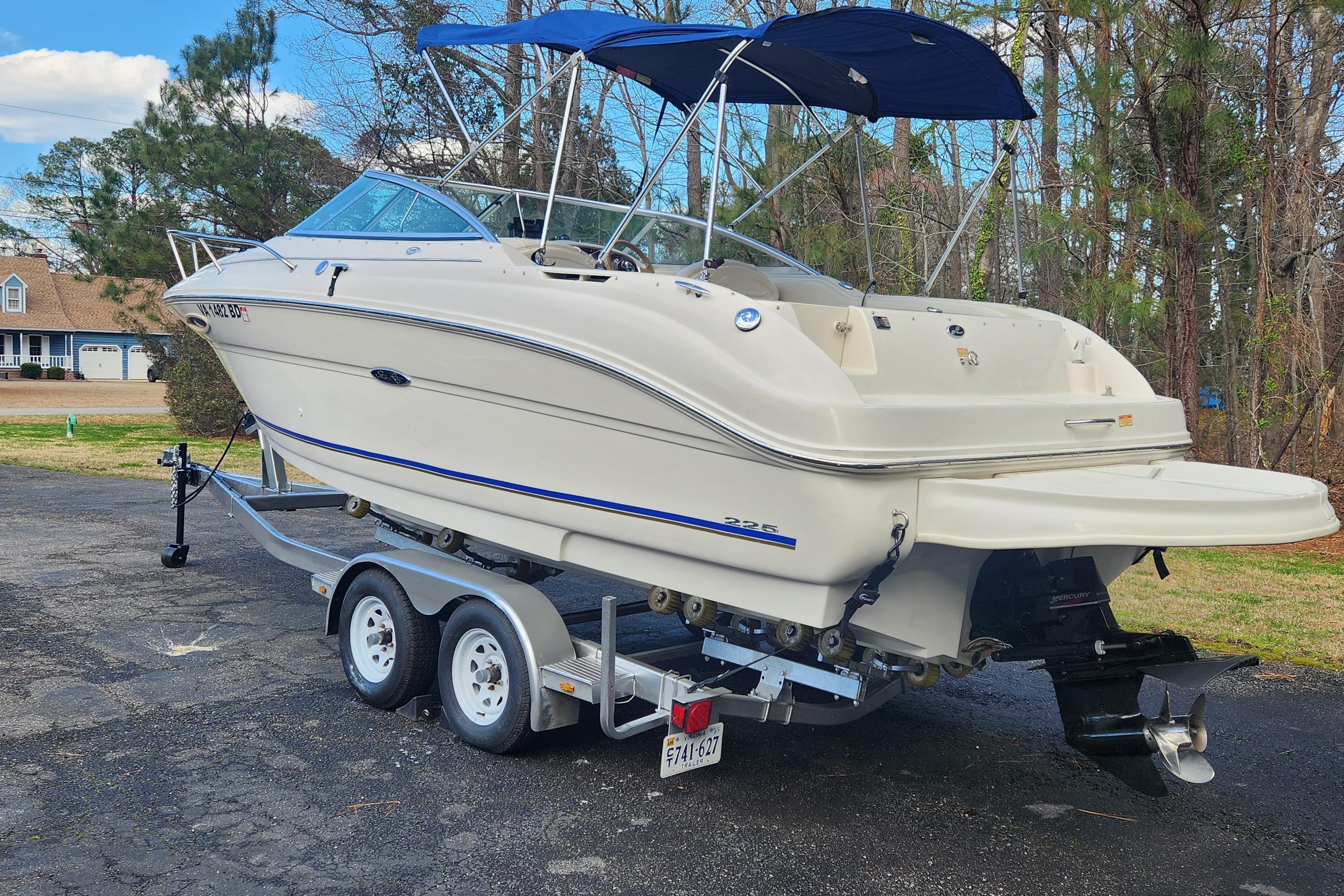 2003 Sea Ray 225 Weekender boat on trailer, parked outdoors with trees in background.