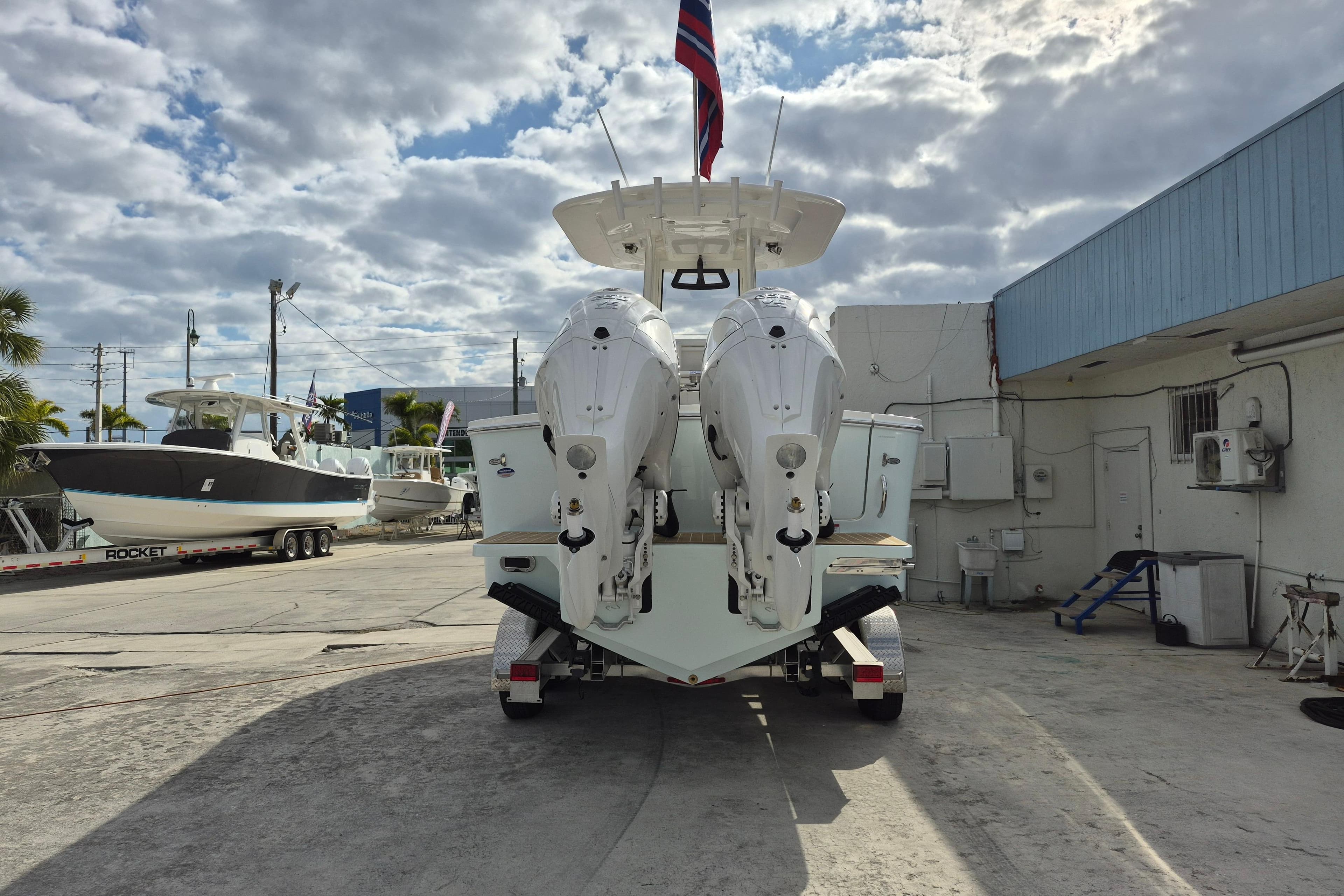 2026 Regulator 25 boat with dual engines on a trailer, under a cloudy sky.