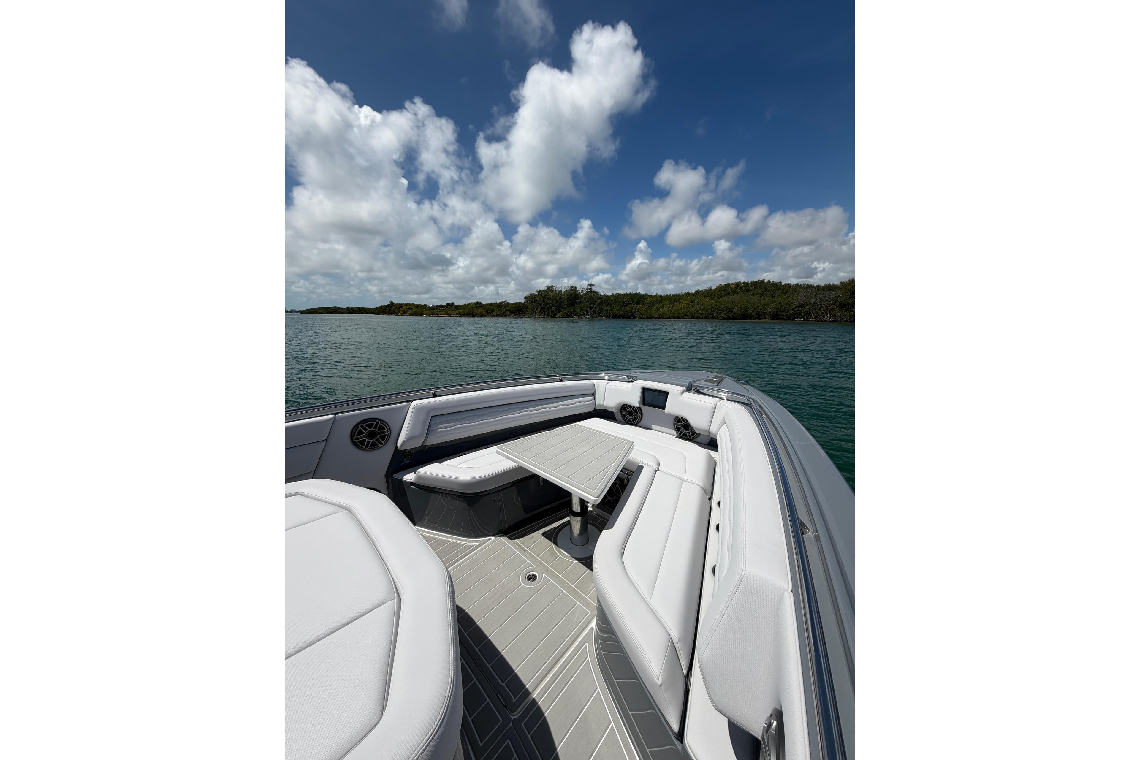 2026 Cigarette 42' Auroris boat interior with sleek seating and table, set against a scenic water backdrop.