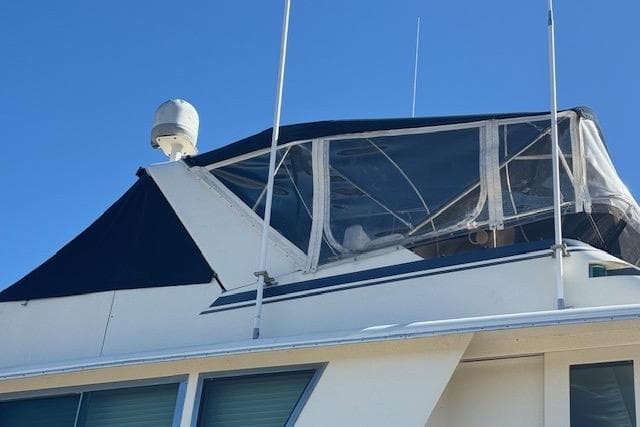 1983 Hatteras 53 Extended Deckhouse Motor Yacht with enclosed upper deck against blue sky.